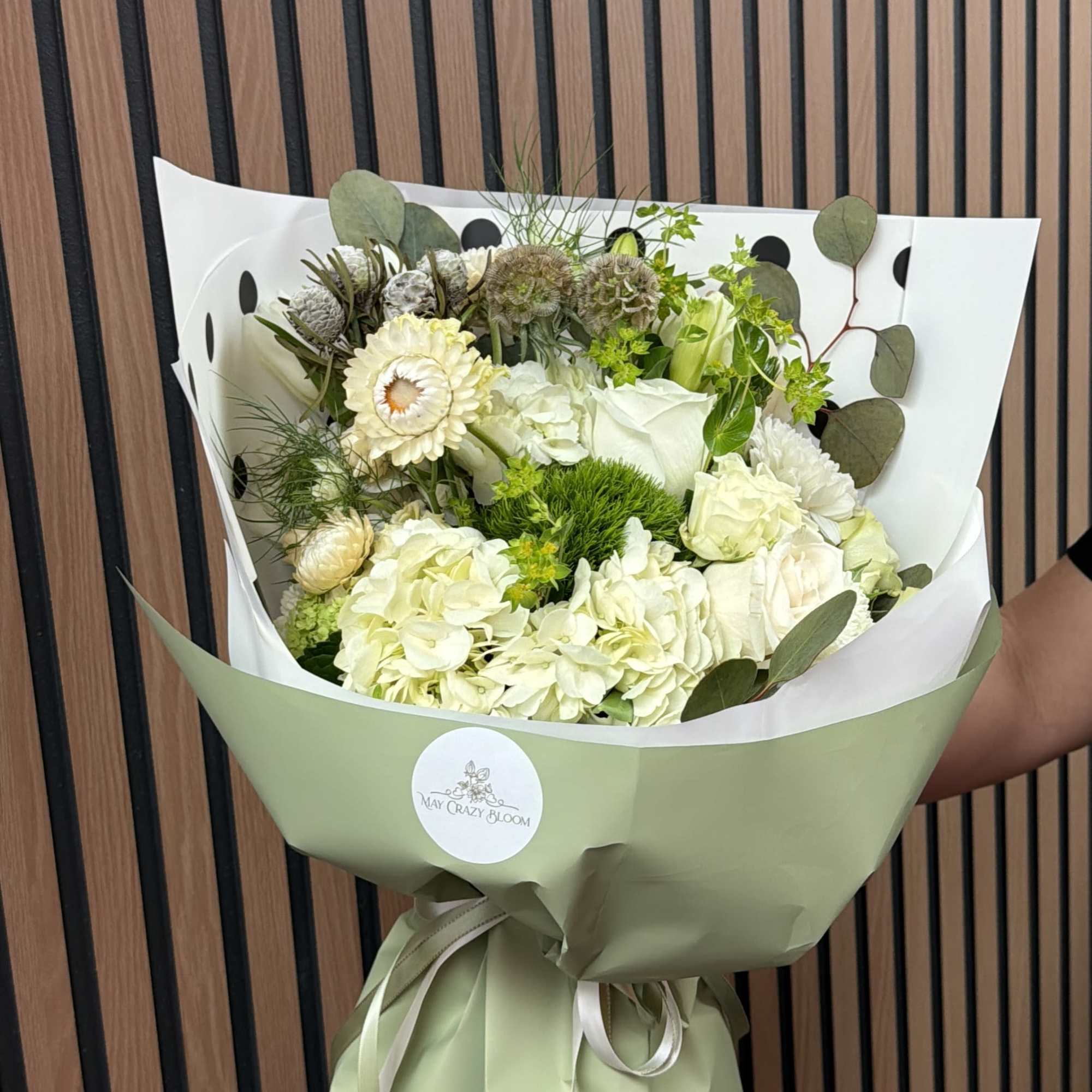 Bouquet of white and pale green flowers wrapped in green paper
