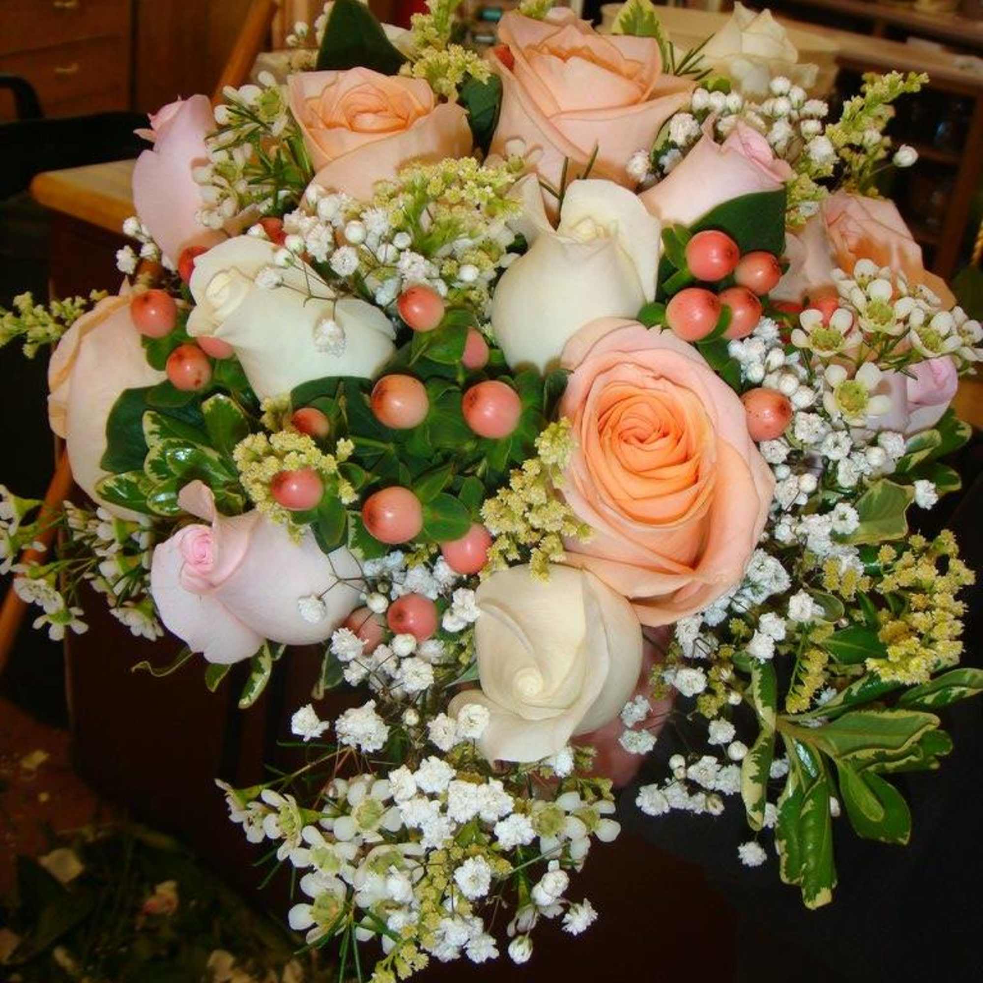Bouquet of peach and white roses with baby's breath and berry accents