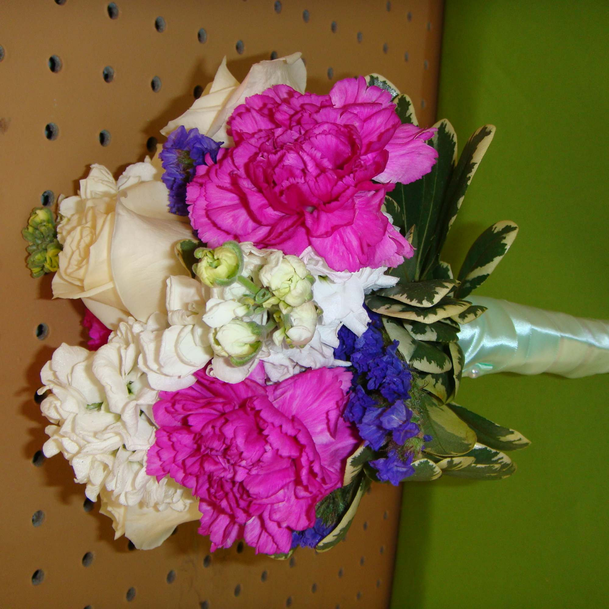 Bouquet of pink and white flowers with blue accents and variegated leaves