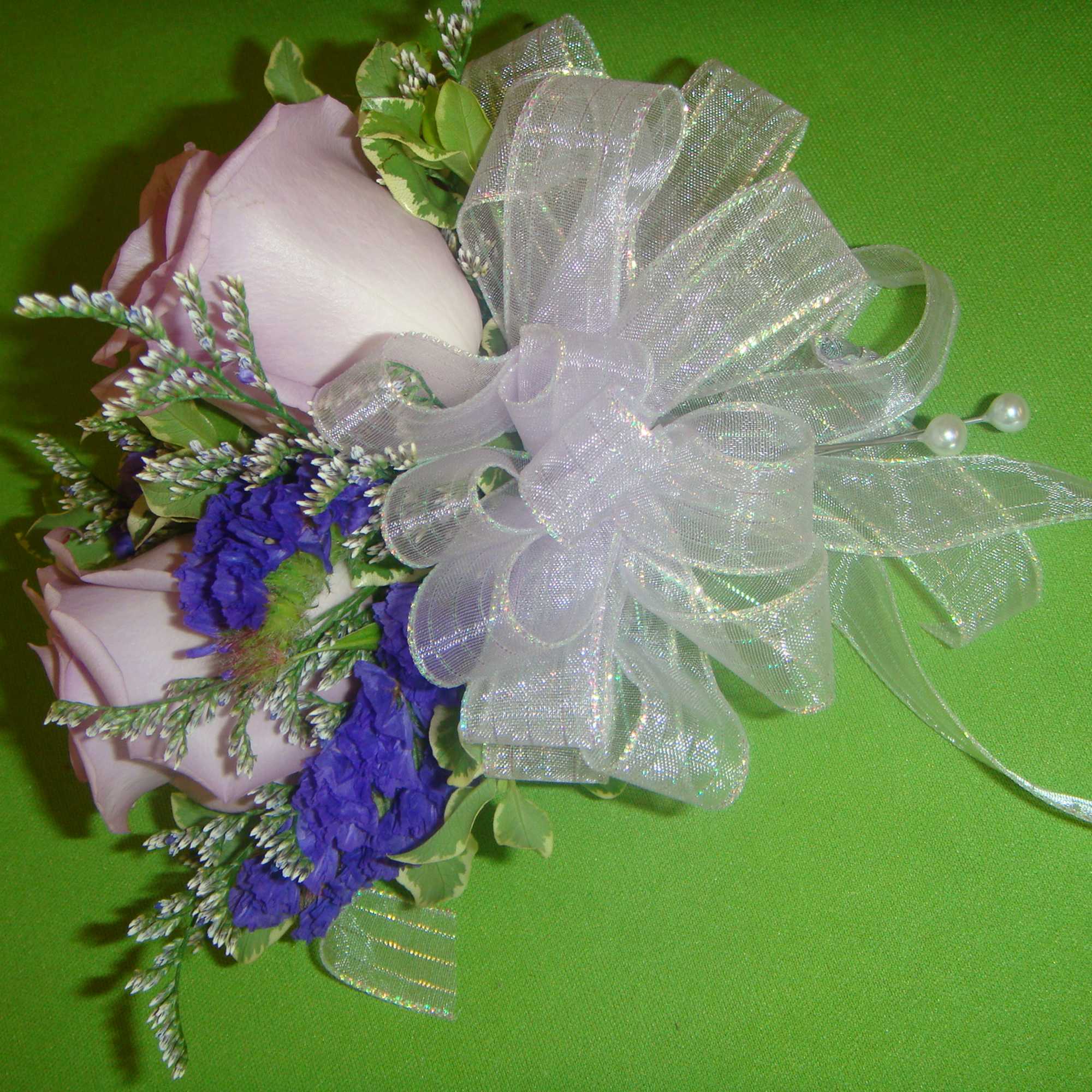 Small bouquet of pale pink roses and purple flowers with a sheer white bow