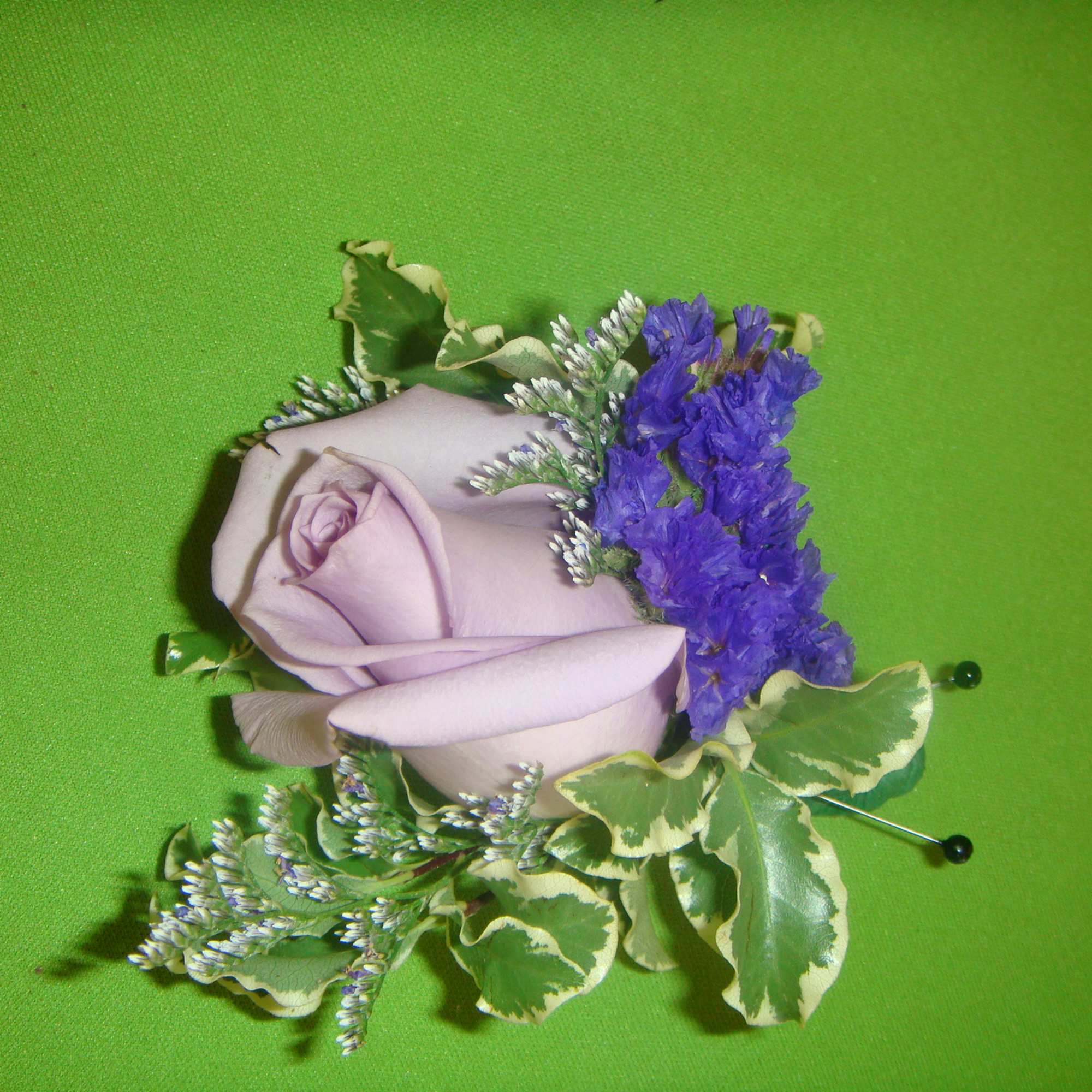 Lavender rose boutonniere with purple filler flowers and variegated greenery