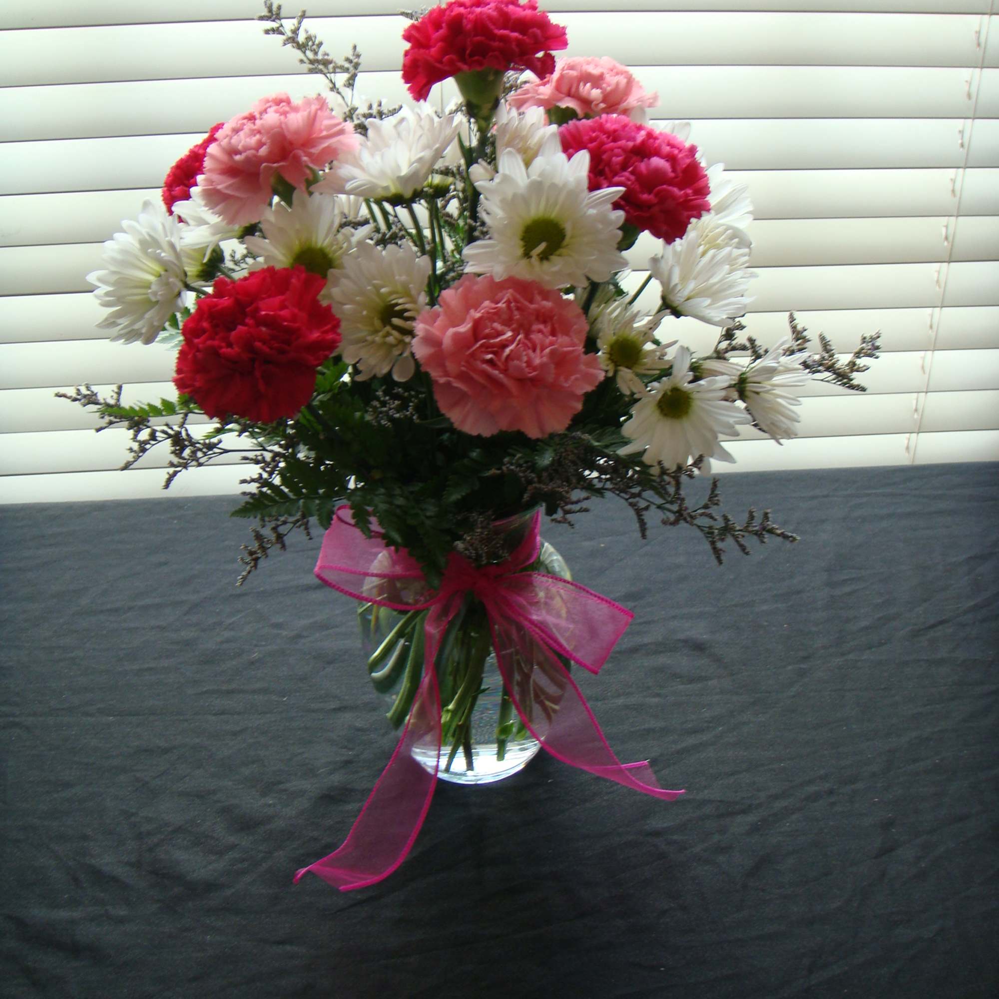 Bouquet of pink and white carnations with daisies in a glass vase