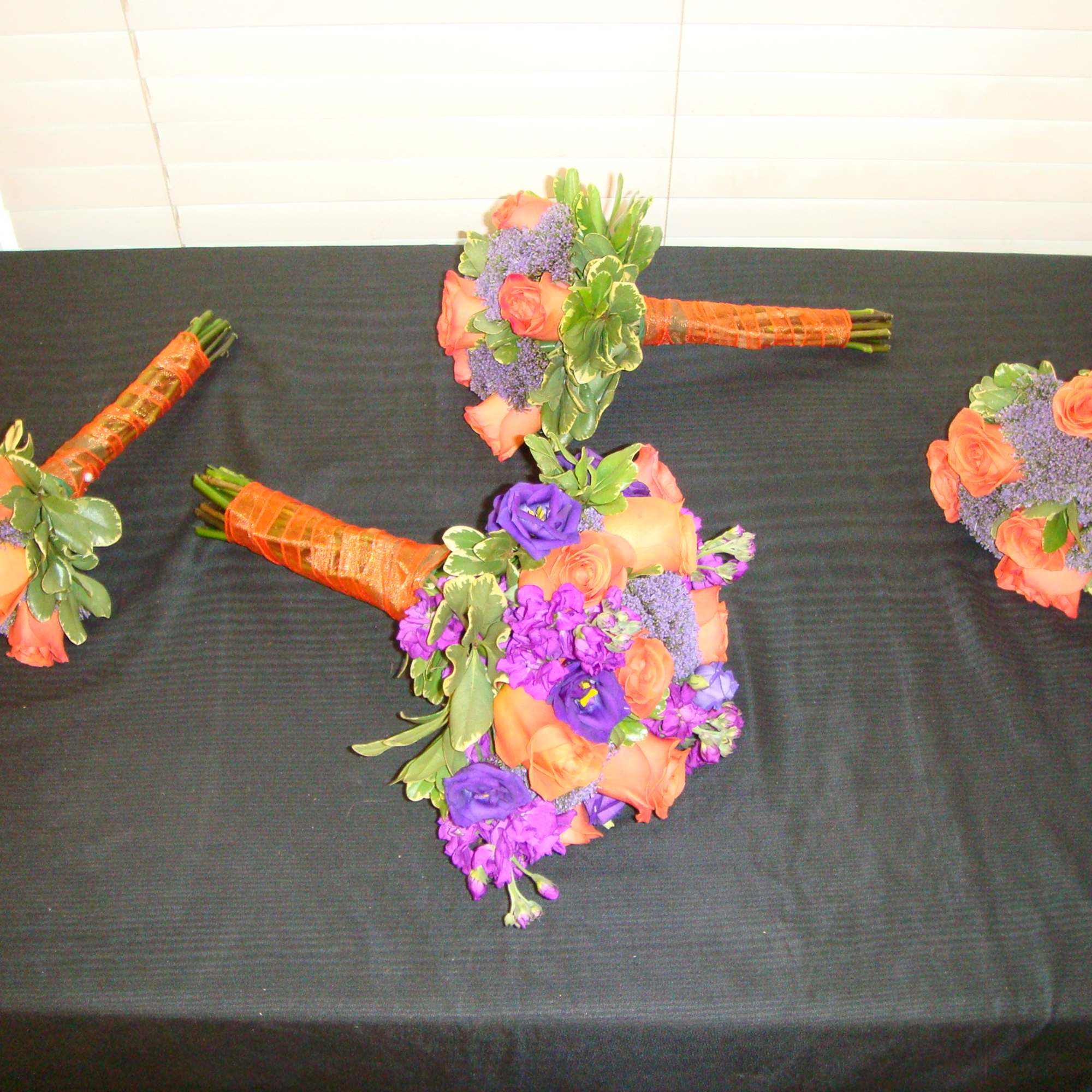 Three colorful hand-tied bouquets with orange and purple flowers