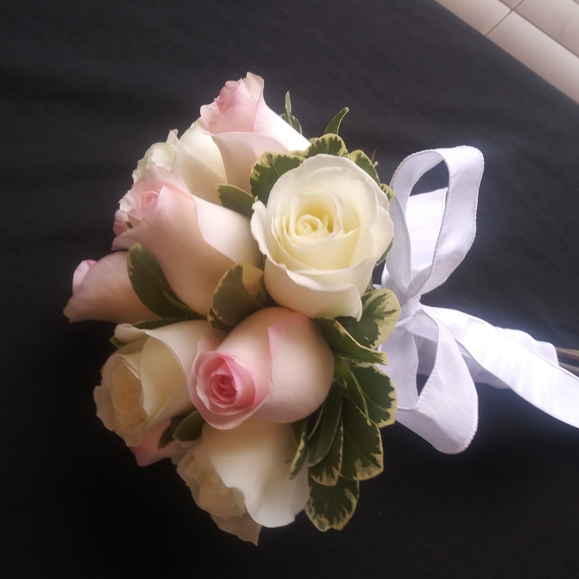 Small bouquet of pink and white roses tied with a white ribbon