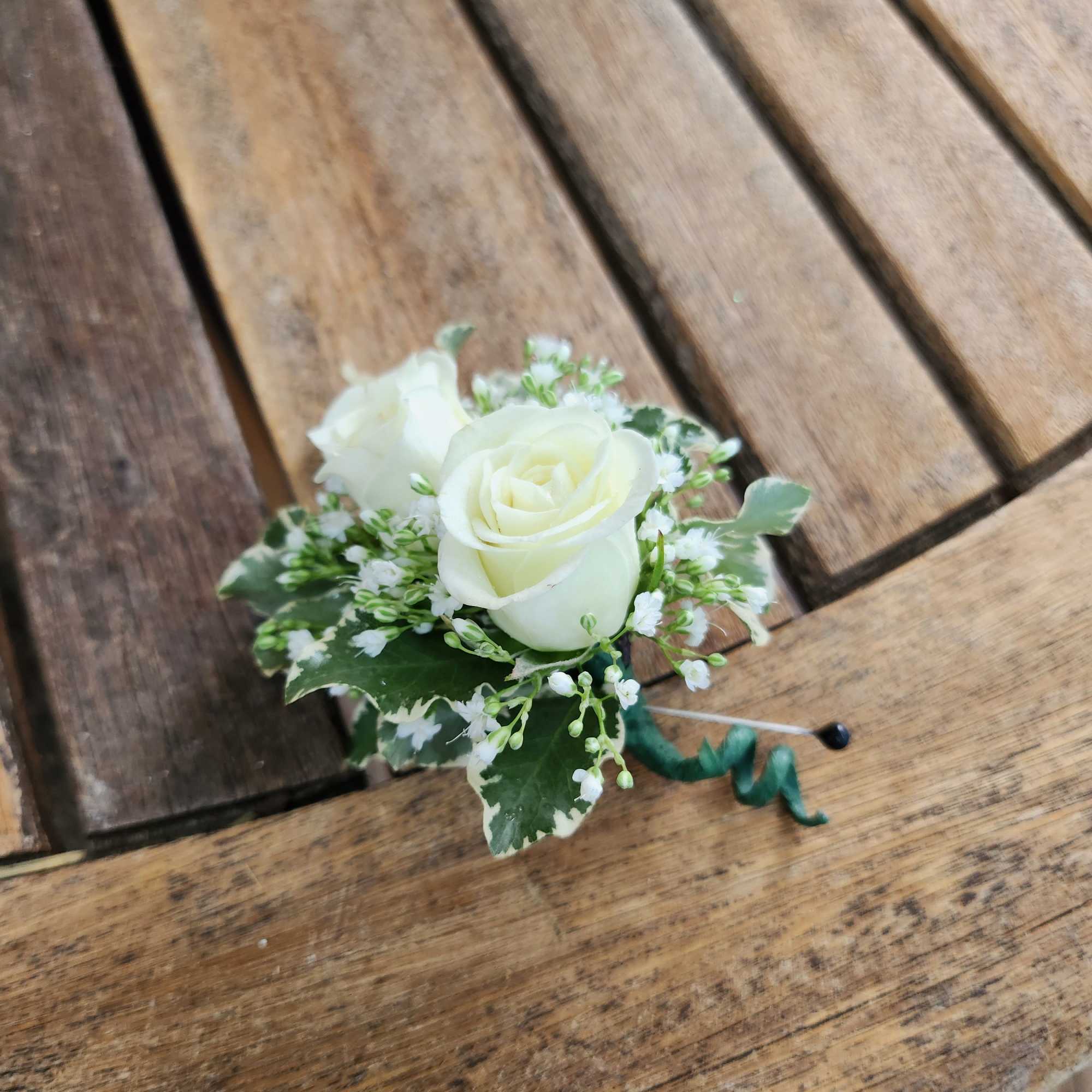 White rose boutonniere with baby's breath and greenery