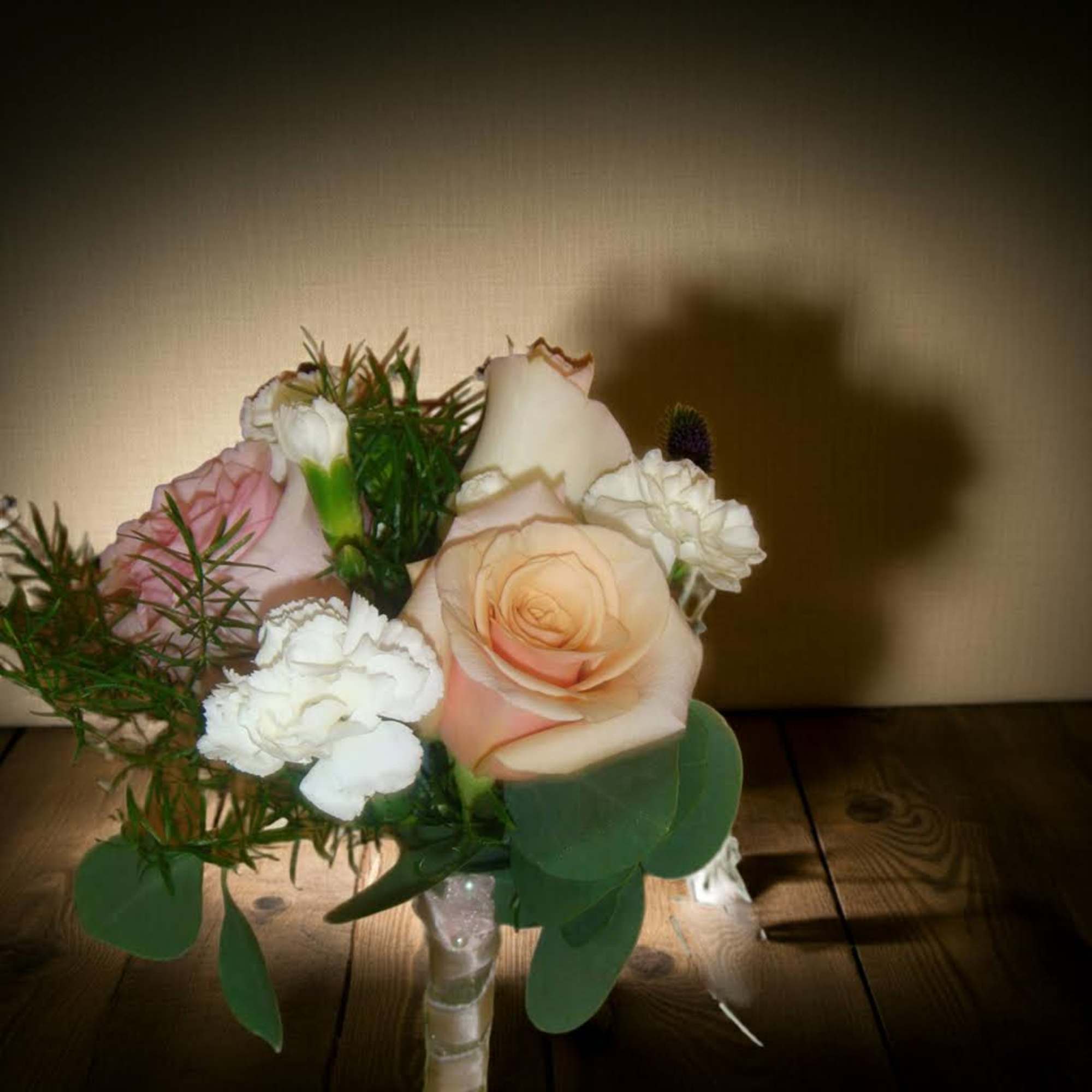 Small bouquet of pale roses and white carnations in a clear wrapped handle