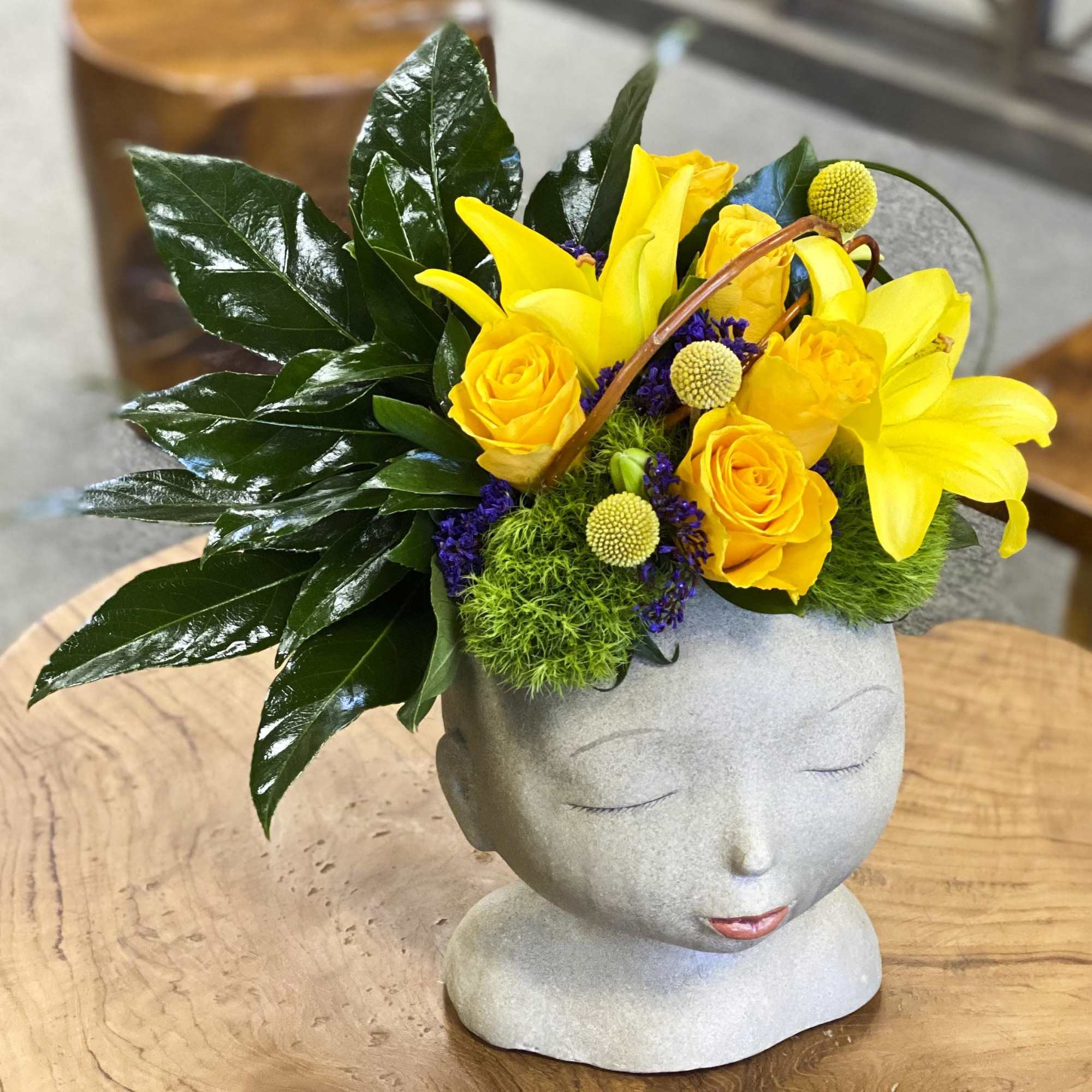 Yellow floral arrangement in a gray face-shaped vase