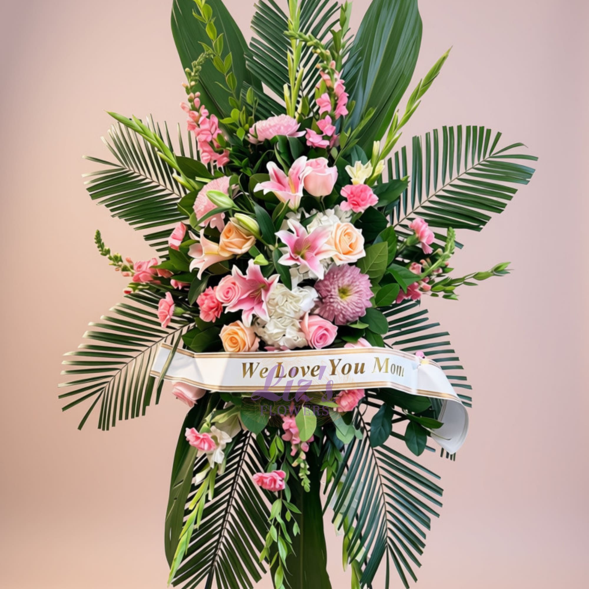 Tall pink and white floral standing arrangement with a ribbon reading We Love You Mom