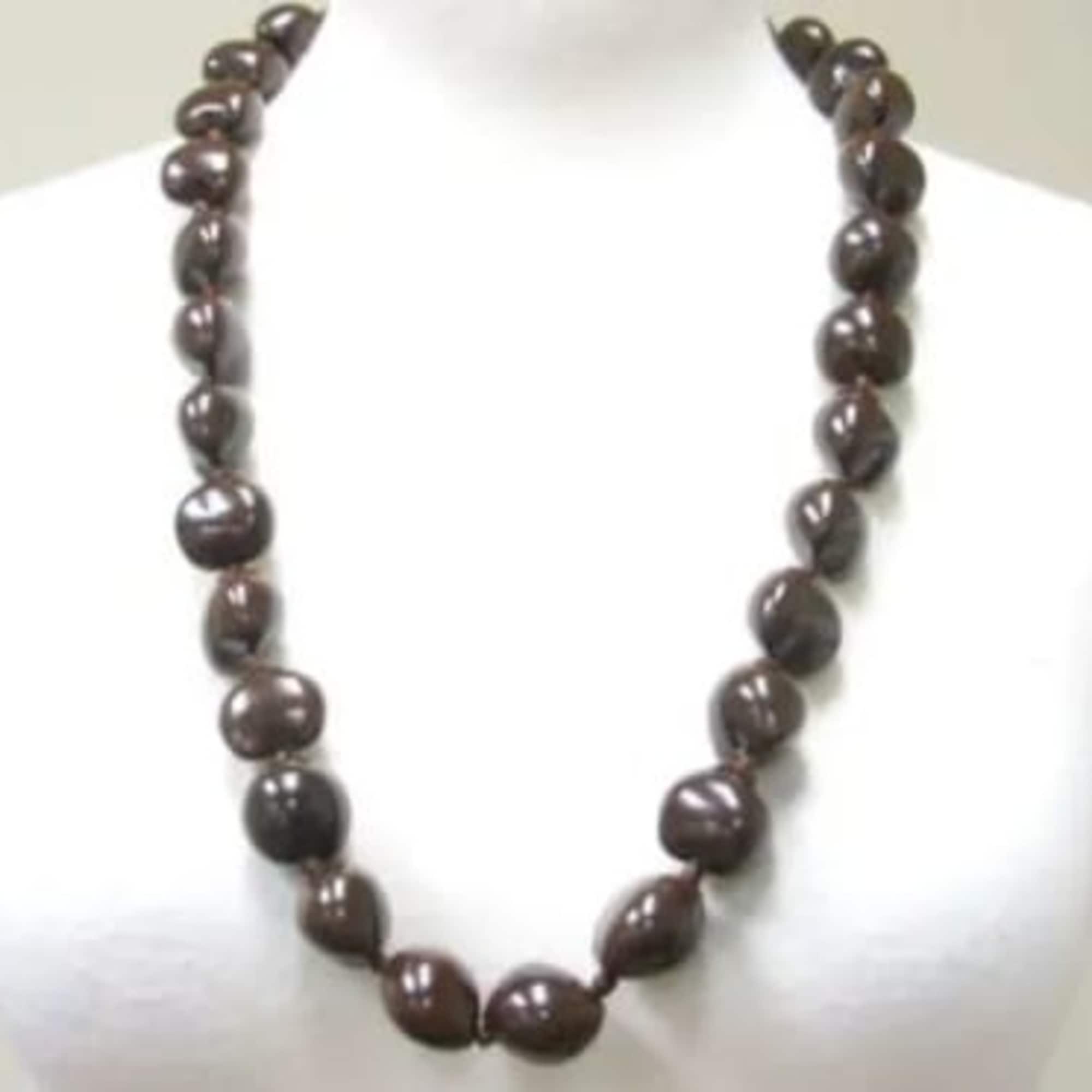 Strand of large dark brown beads forming a necklace on a white display bust