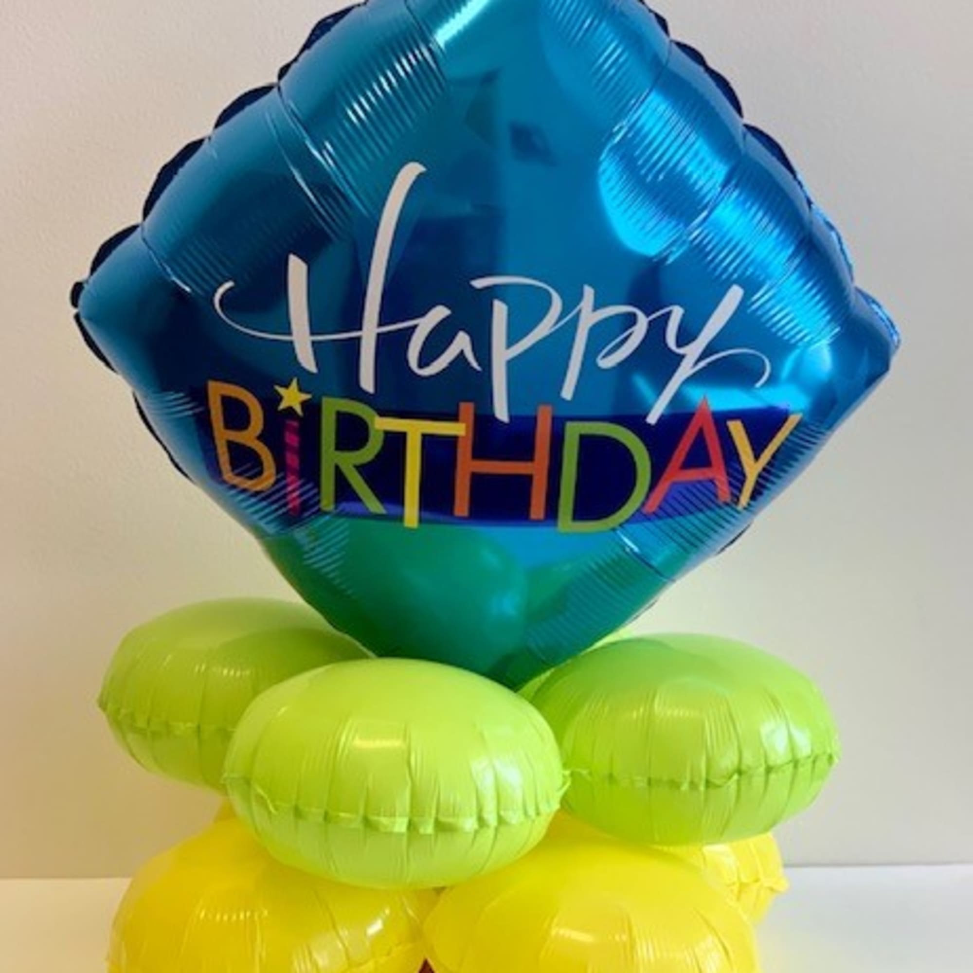 Blue Happy Birthday balloon above lime and yellow balloons