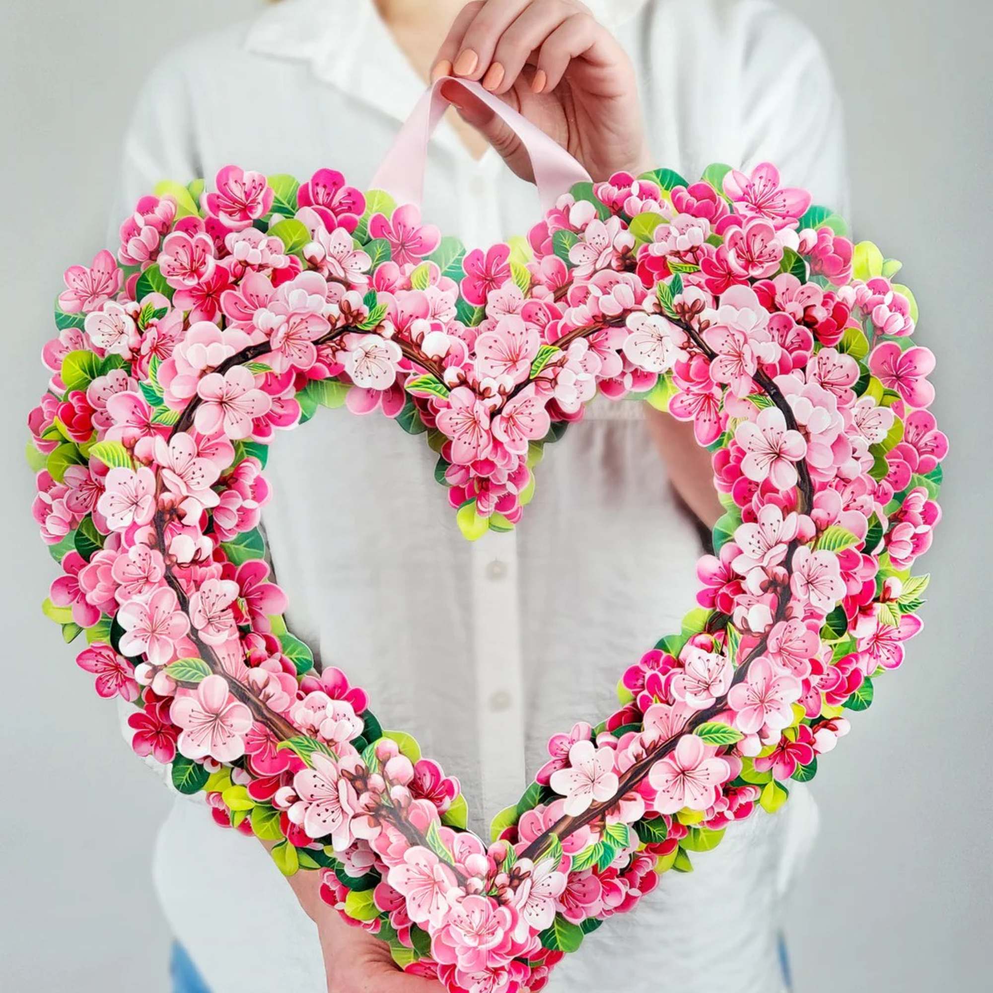 Heart-shaped floral wreath with pink blossoms and green accents