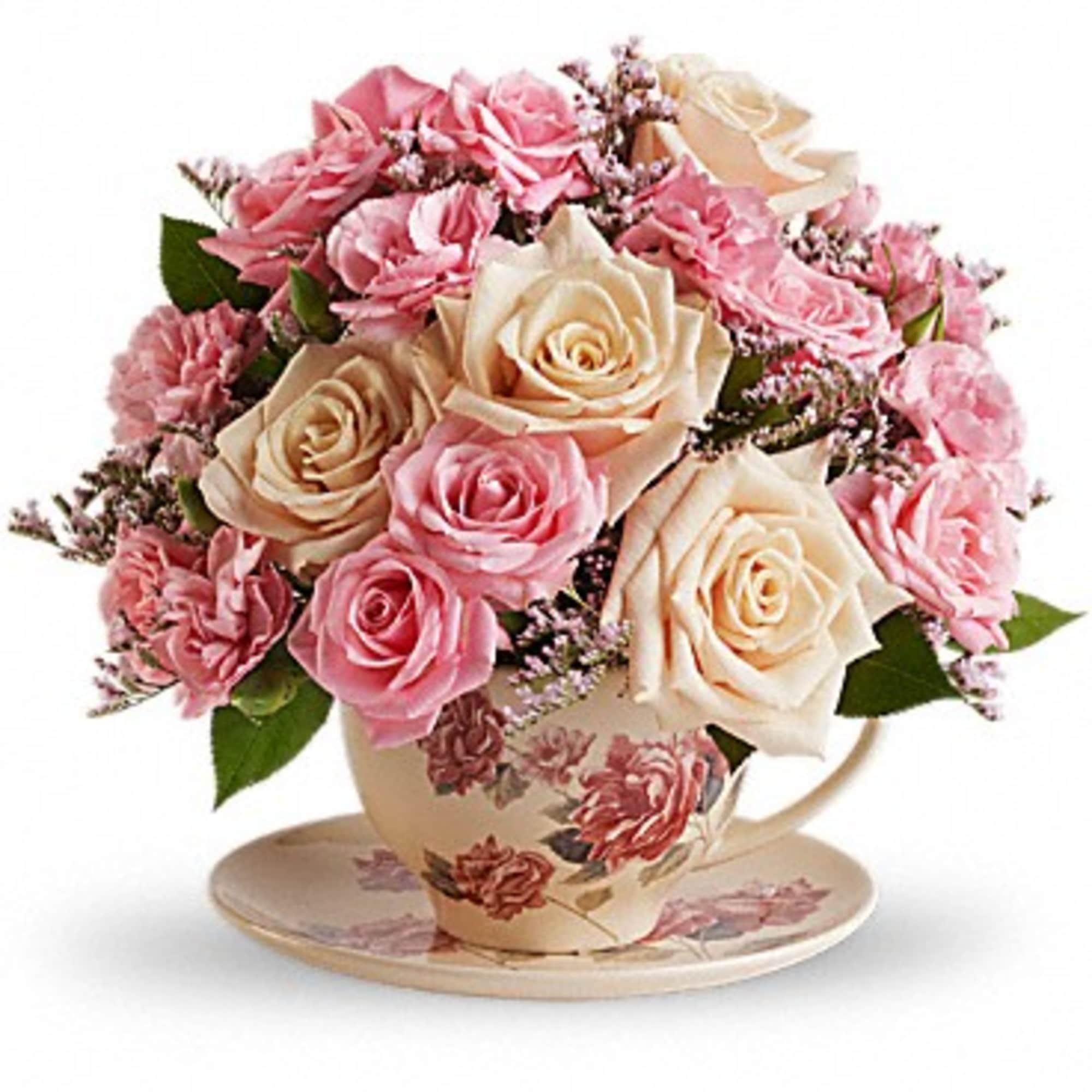 Pink and cream roses arranged in a floral teacup with saucer