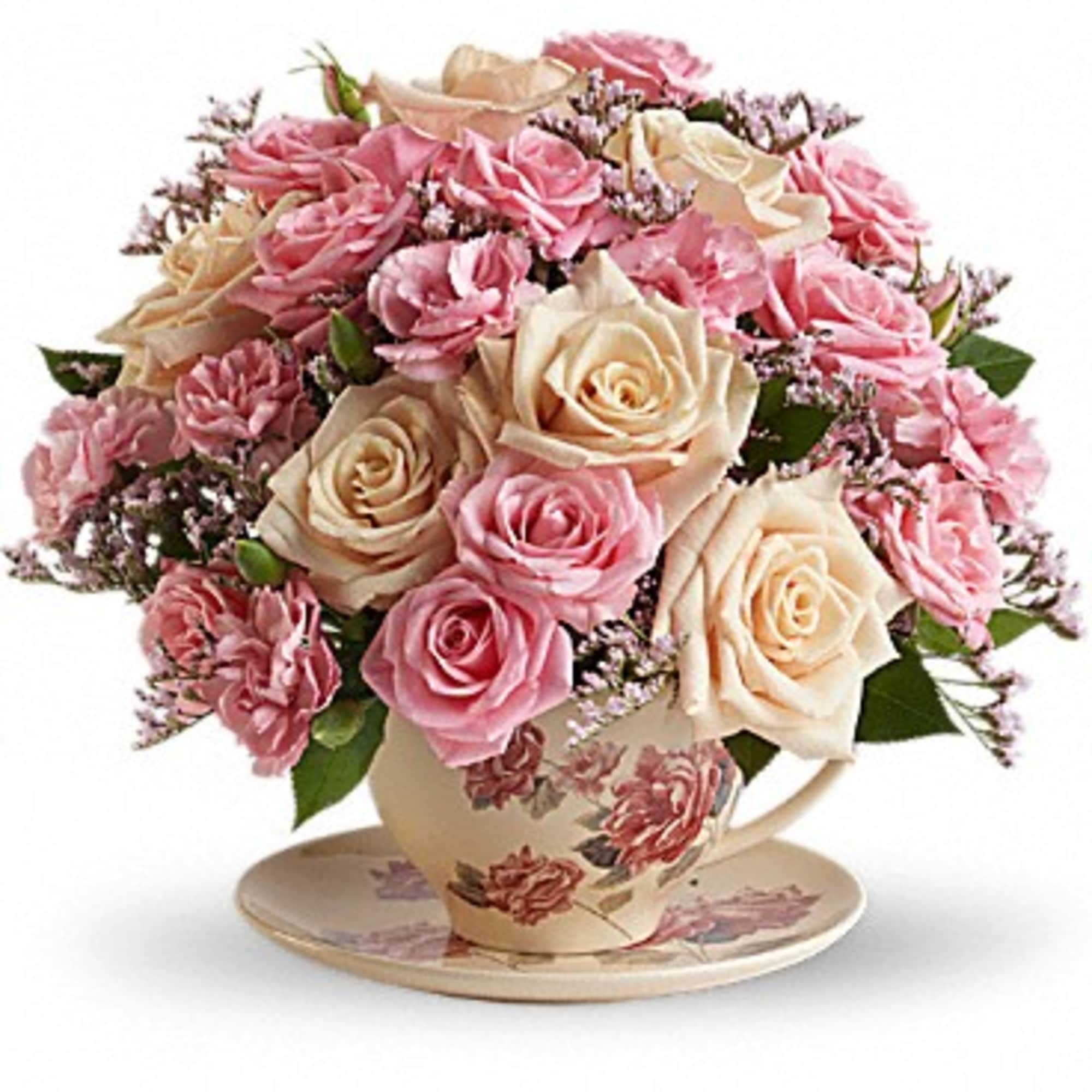 Pink and cream roses arranged in a floral teacup with saucer