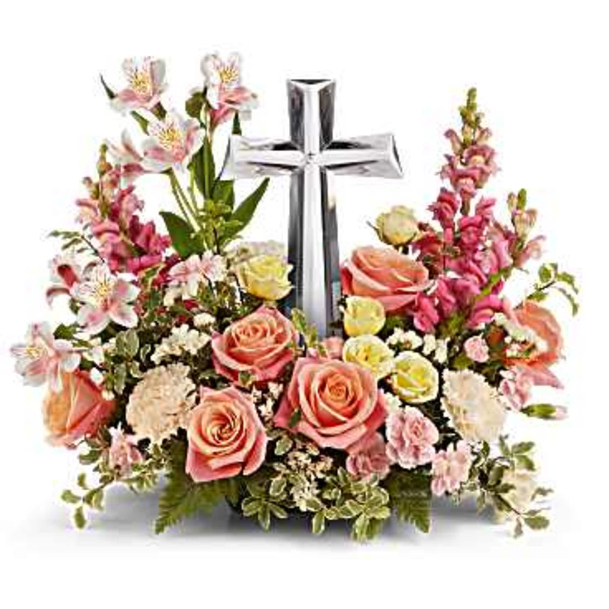 Pink and white floral arrangement with a silver cross centerpiece