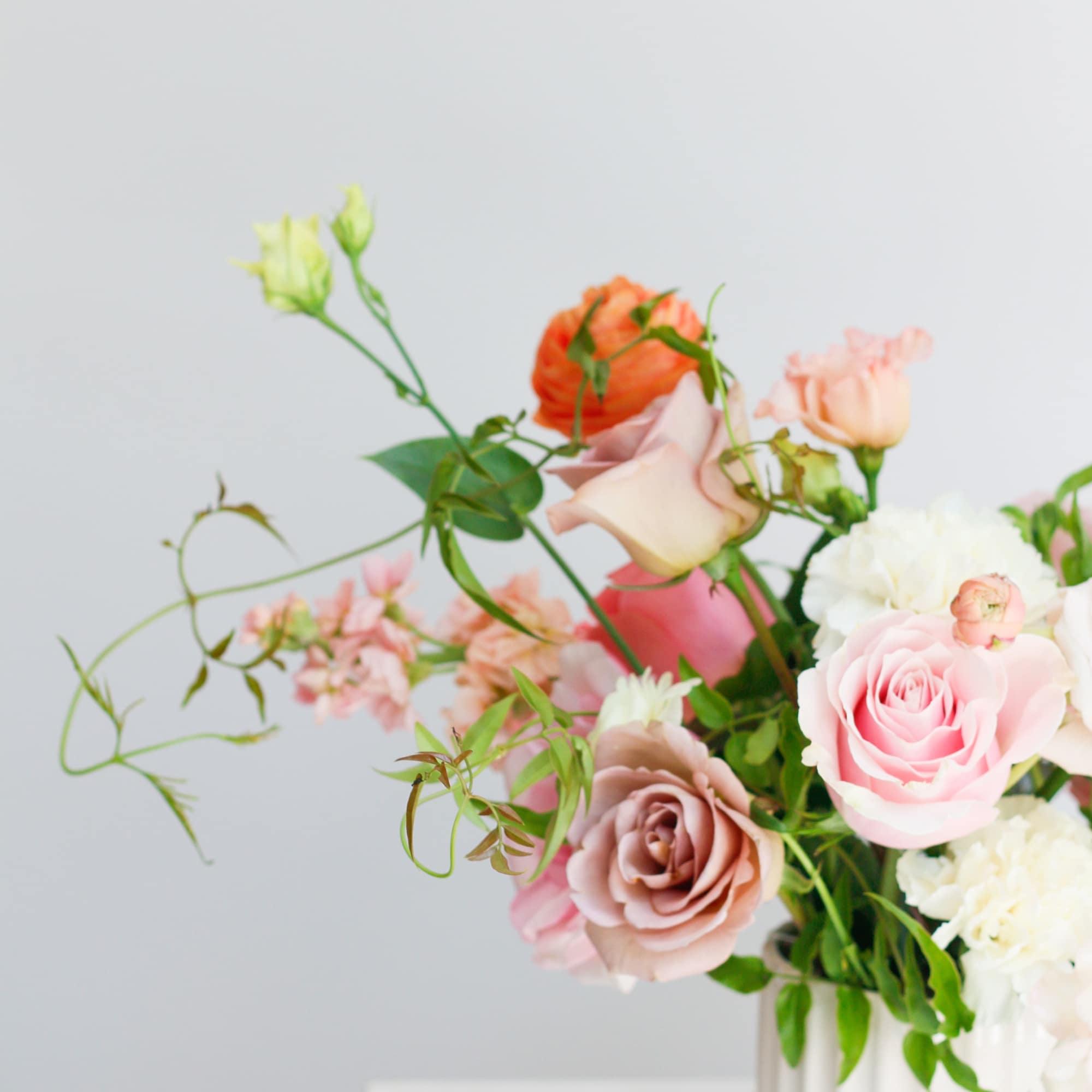 Pastel roses and carnations in a white vase