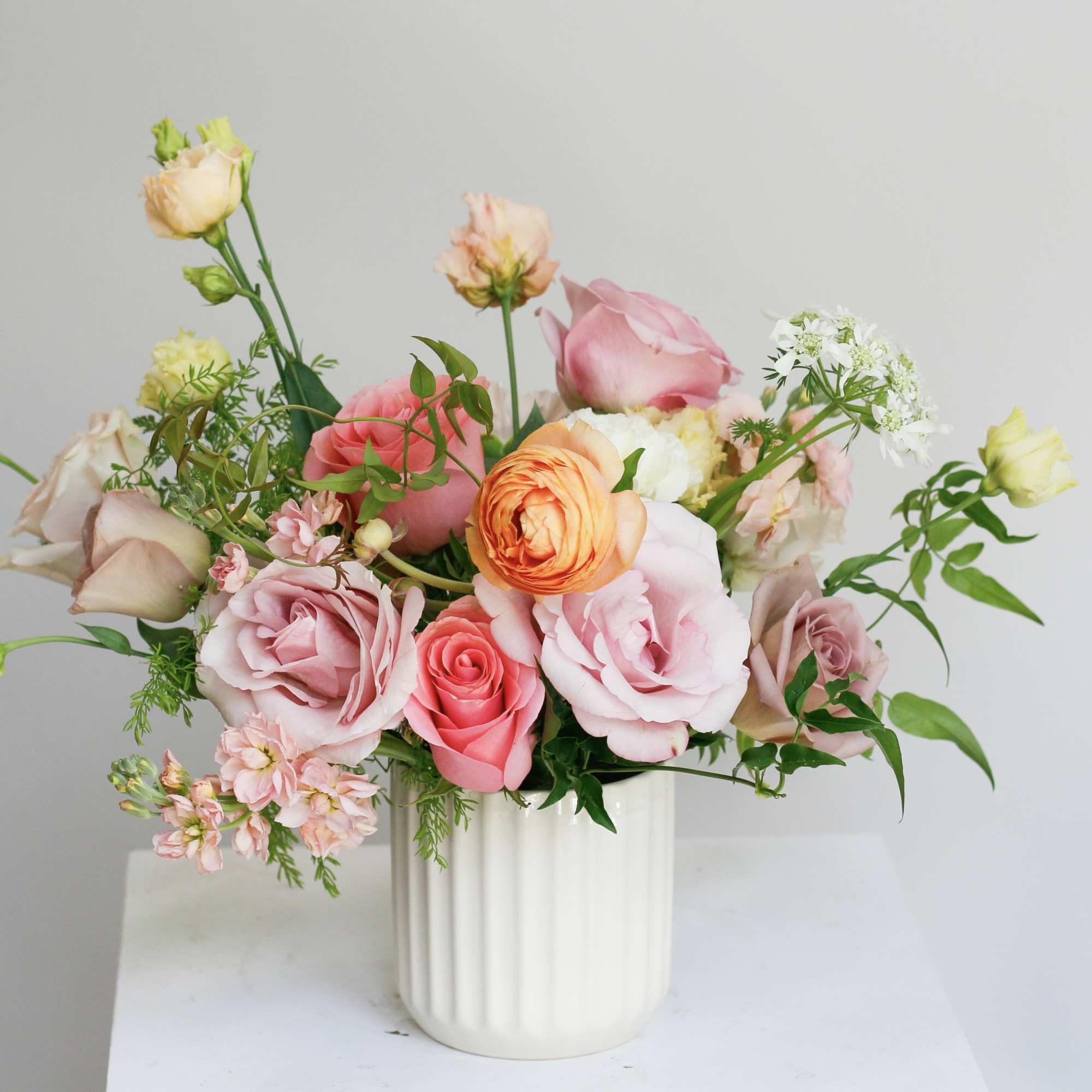 Pink and peach roses arranged in a white vase