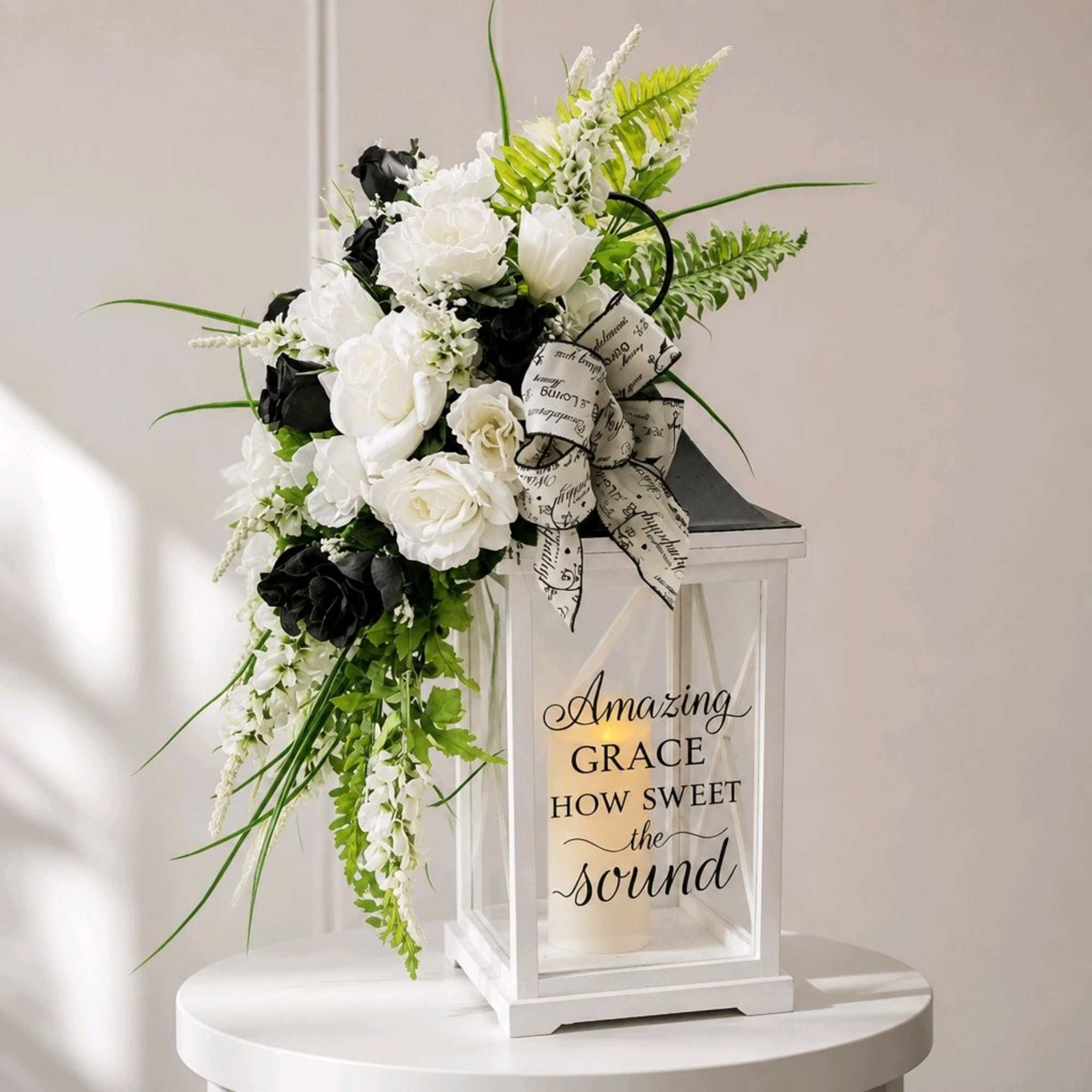 White and black floral arrangement with a ribbon on a lantern