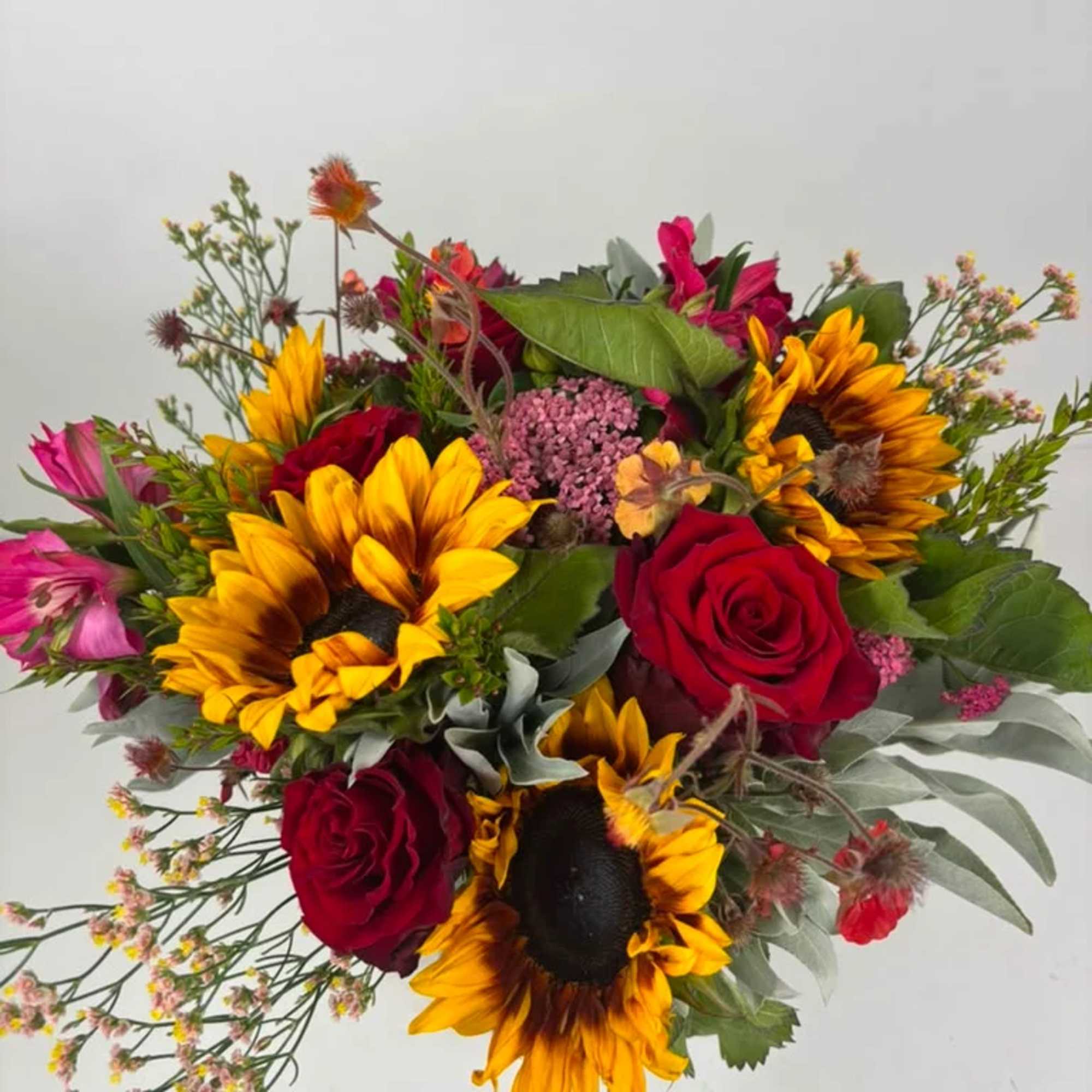 Bouquet of red roses and yellow sunflowers with pink accents