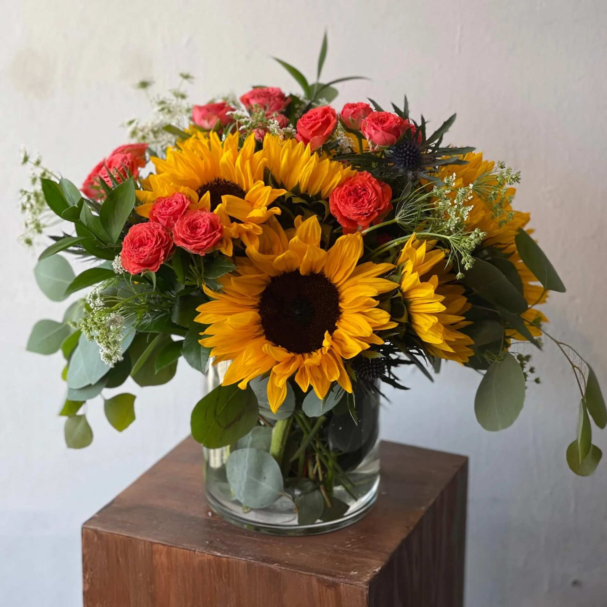 Bouquet of sunflowers and pink roses in a glass vase