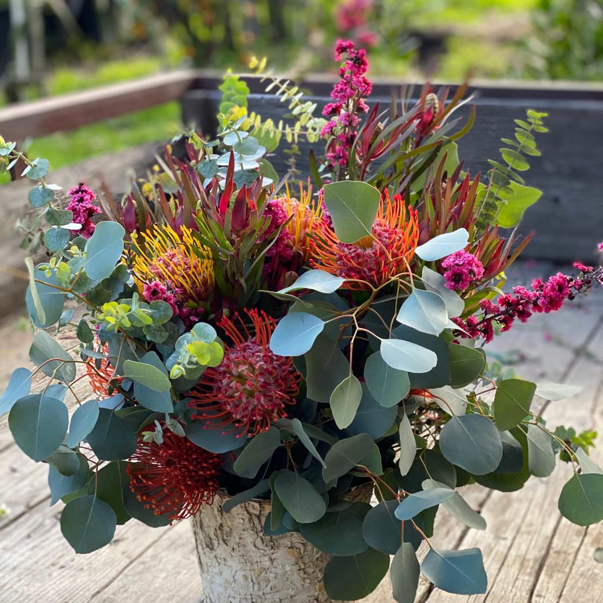 Mixed bouquet with pink and orange blooms in a rustic pot