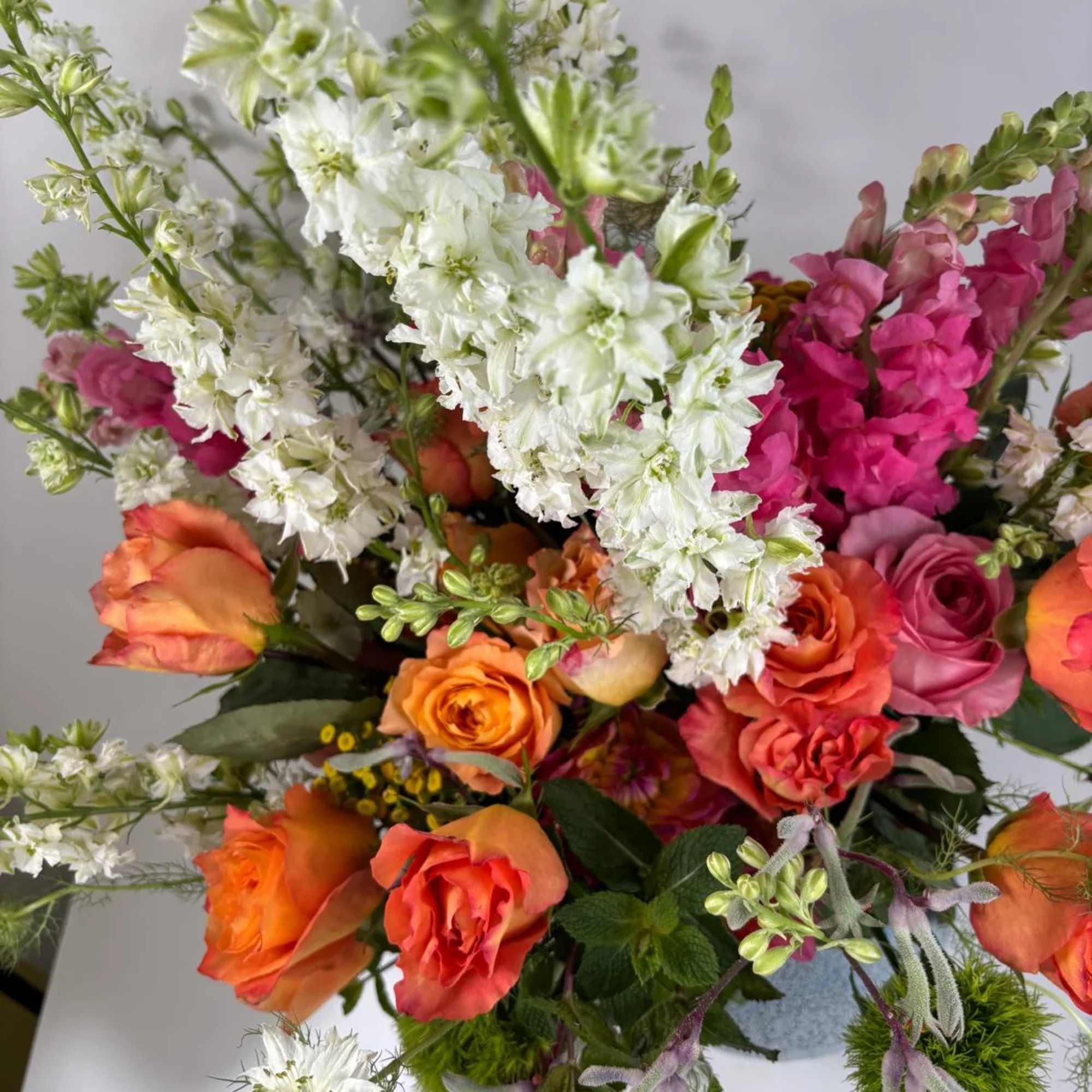 Bouquet of orange and pink roses with white and magenta snapdragons