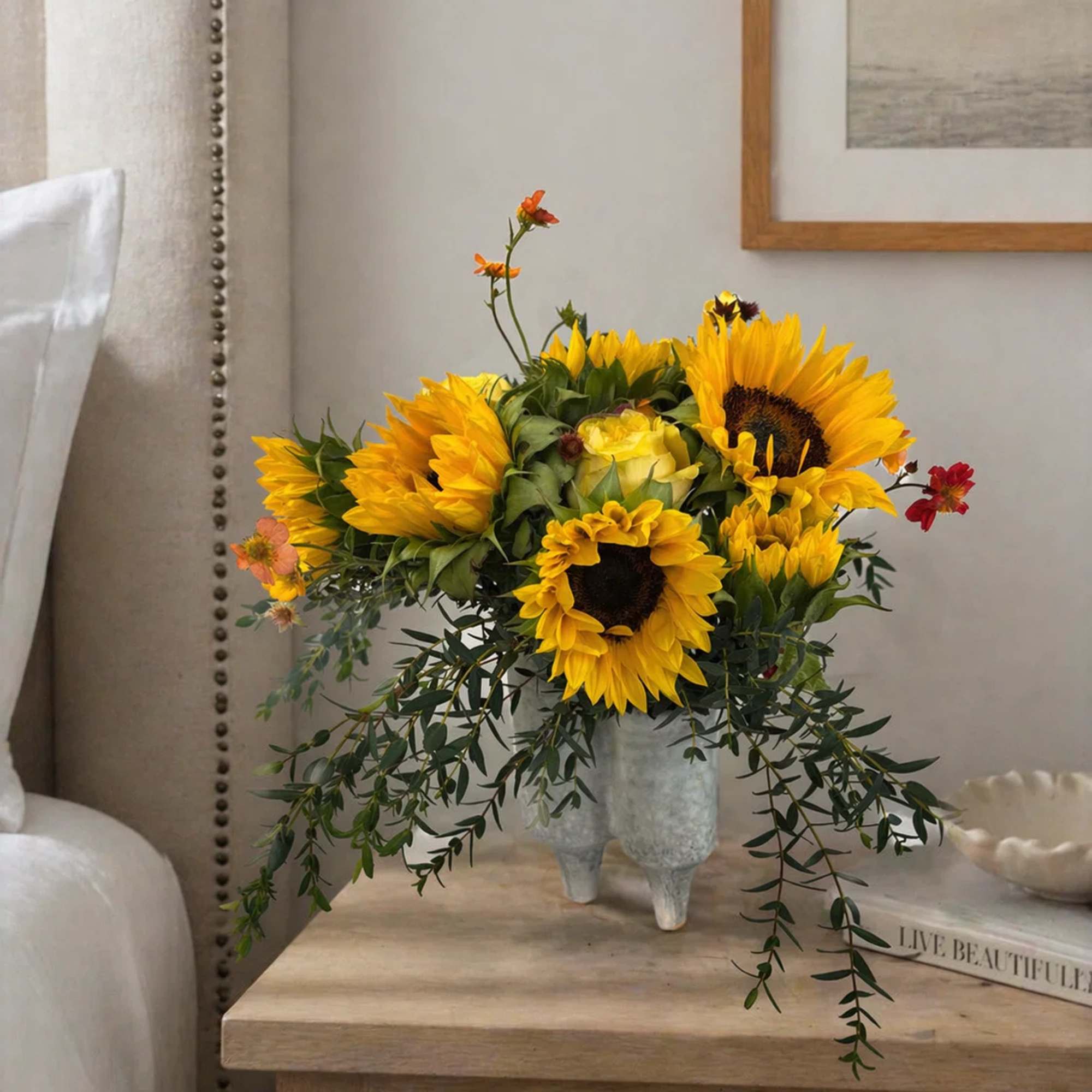Sunflower arrangement in a textured vase on a bedside table