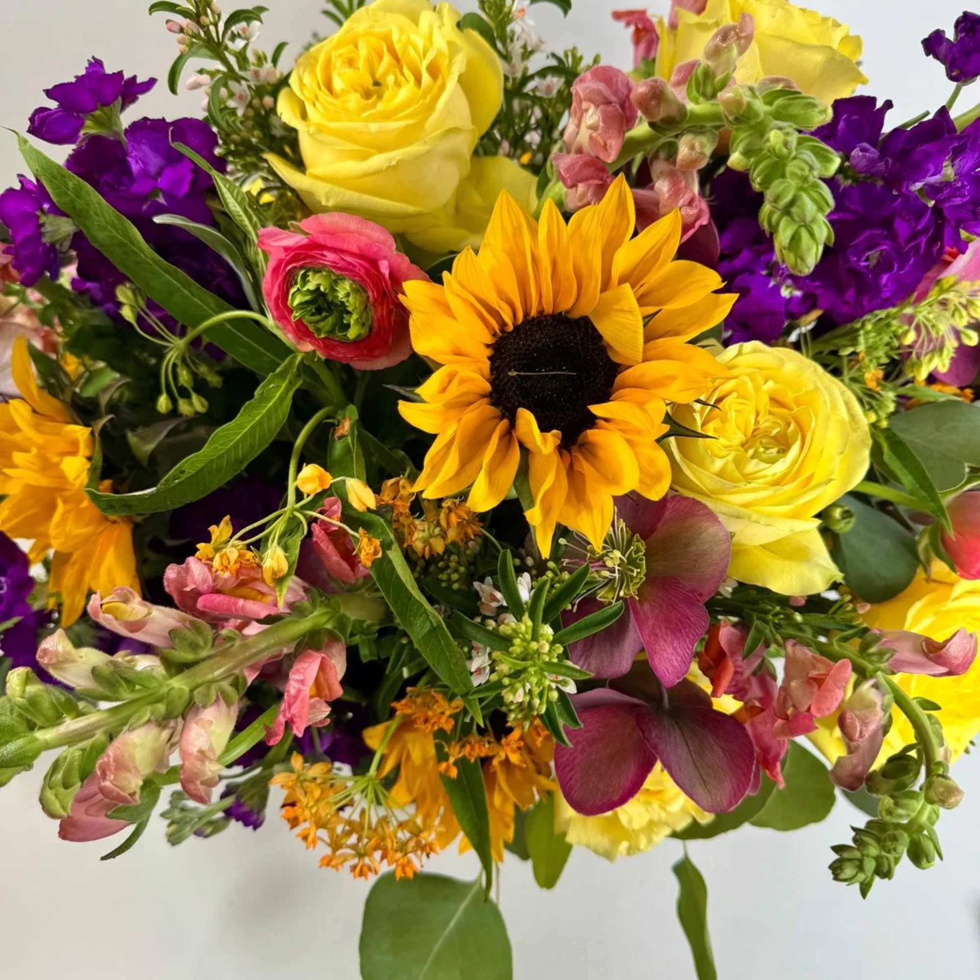 Mixed bouquet with yellow roses, a sunflower, and purple blooms