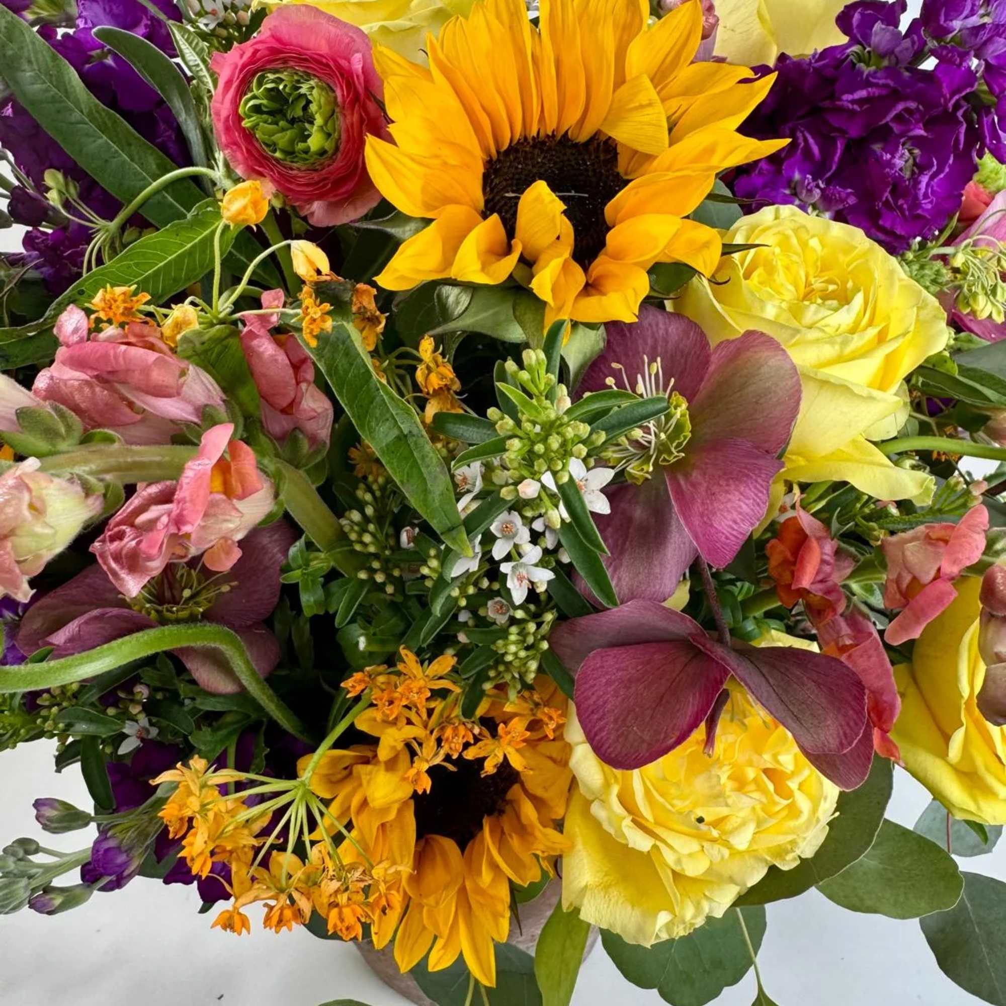 Mixed bouquet with yellow roses, sunflowers, and purple blooms