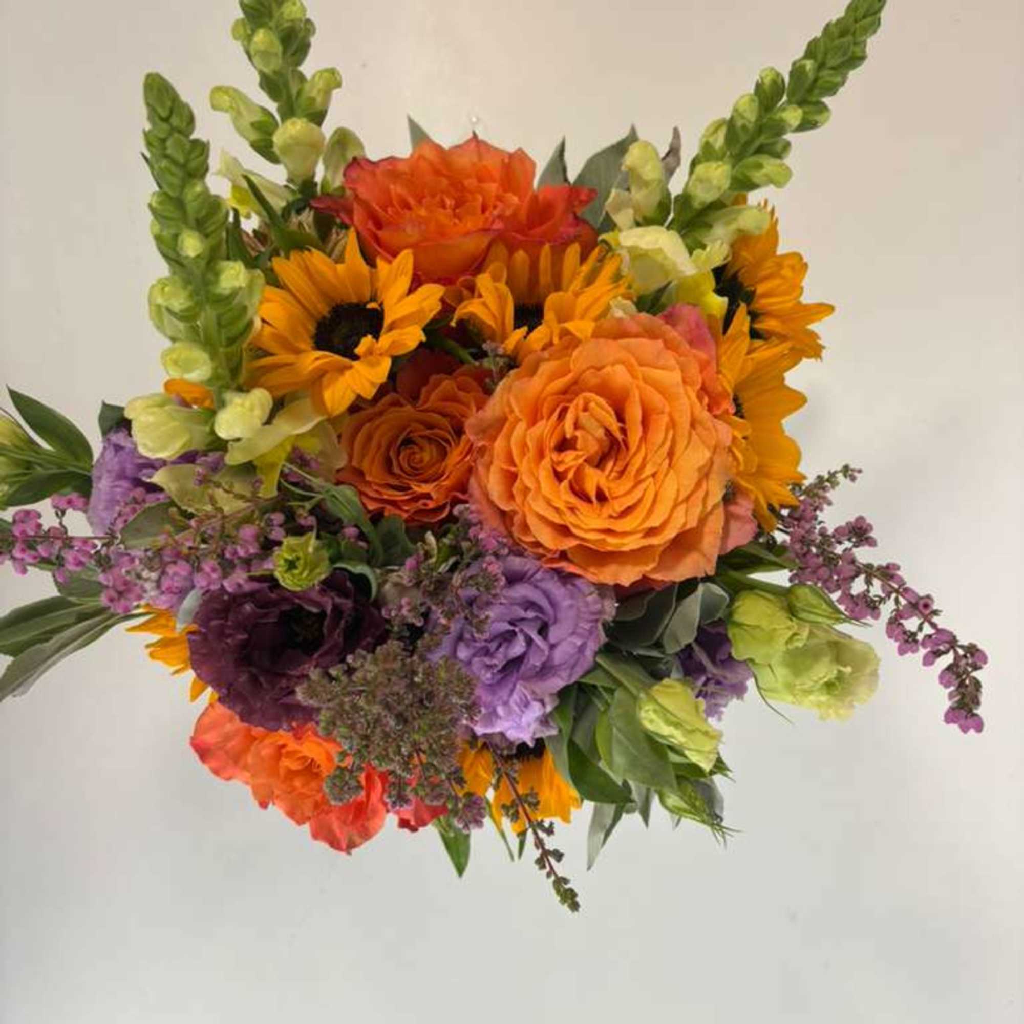 Bright mixed bouquet with orange roses, sunflowers, and purple blooms