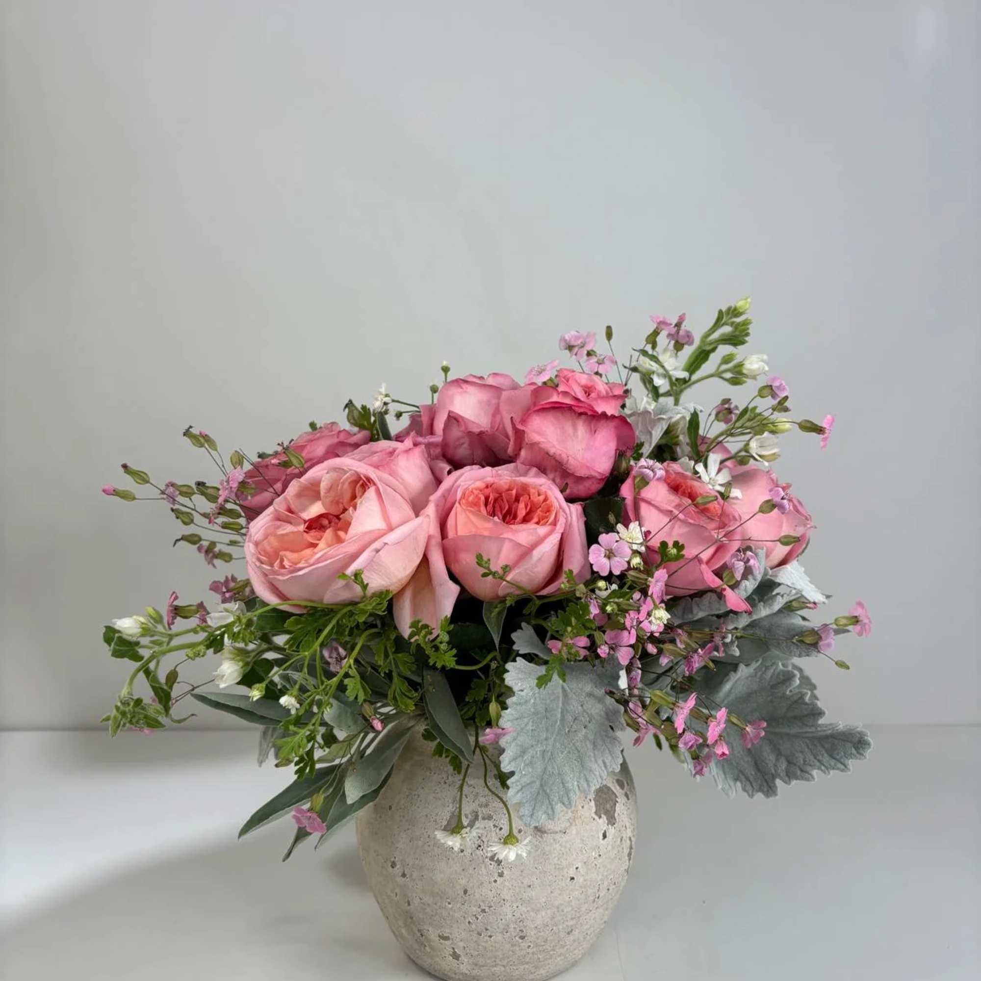 Pink rose arrangement in a textured ceramic vase