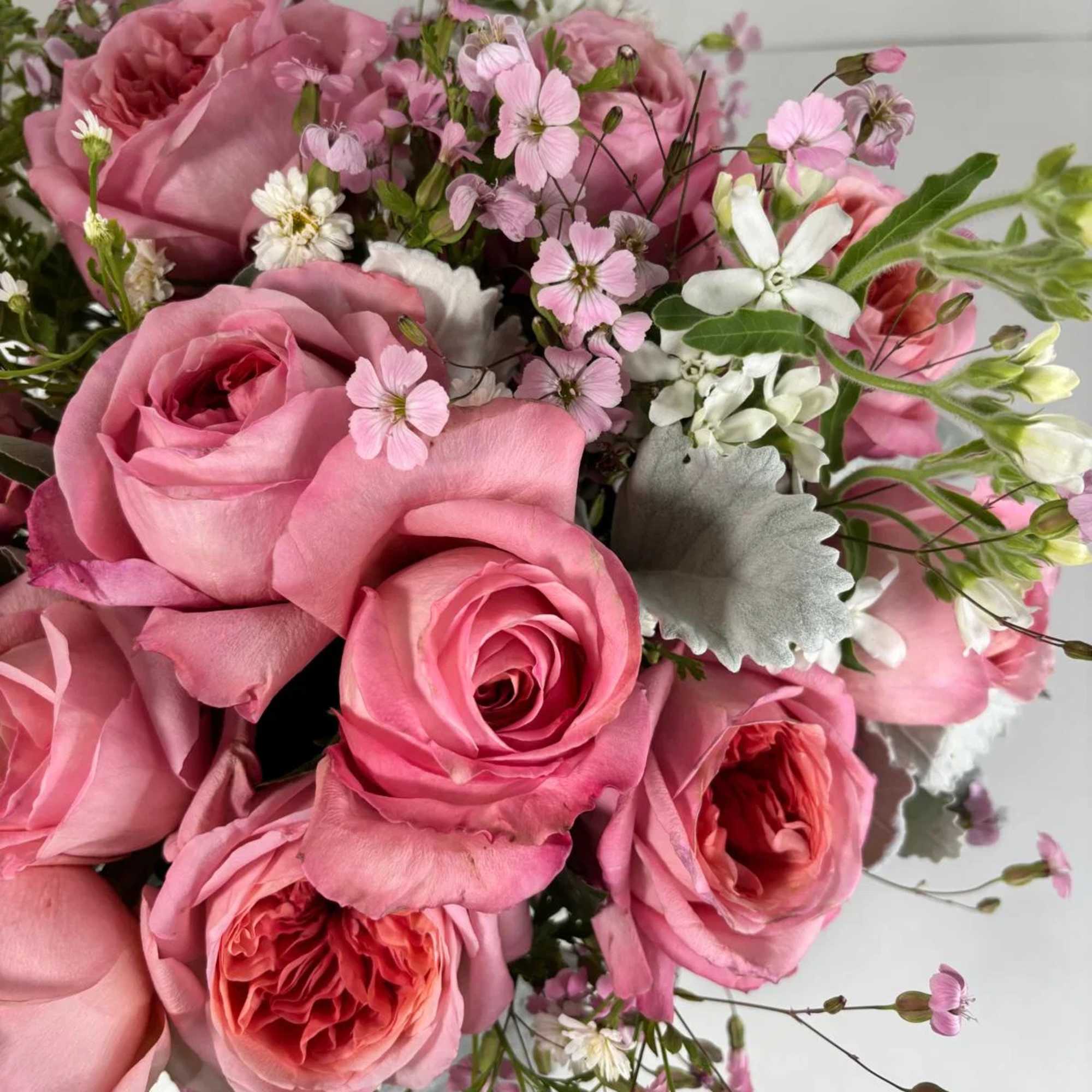 Pink roses with small white and pink filler flowers in a bouquet