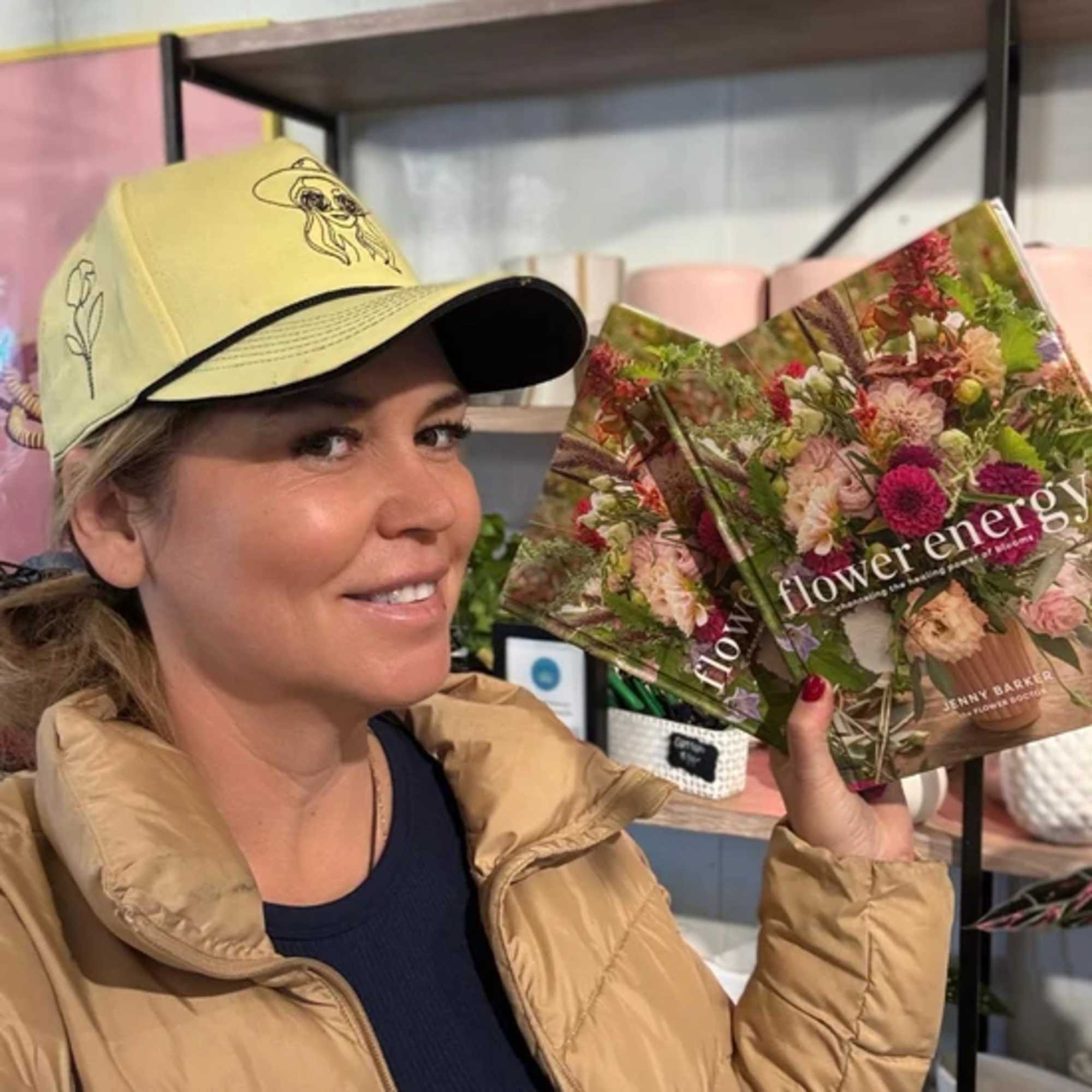 Woman holding two flower-themed books in a shop