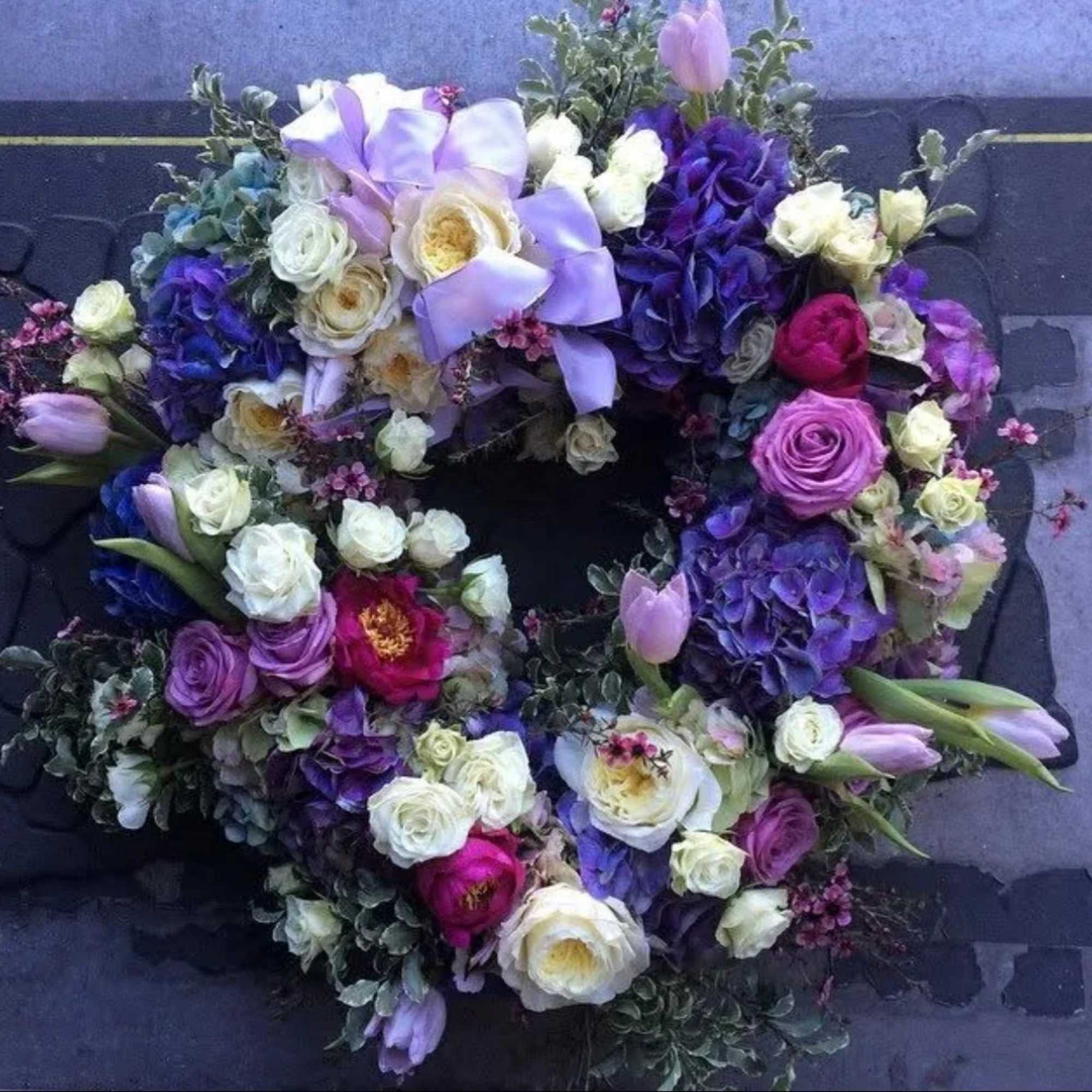 Circular floral wreath with purple, white, and pink blooms