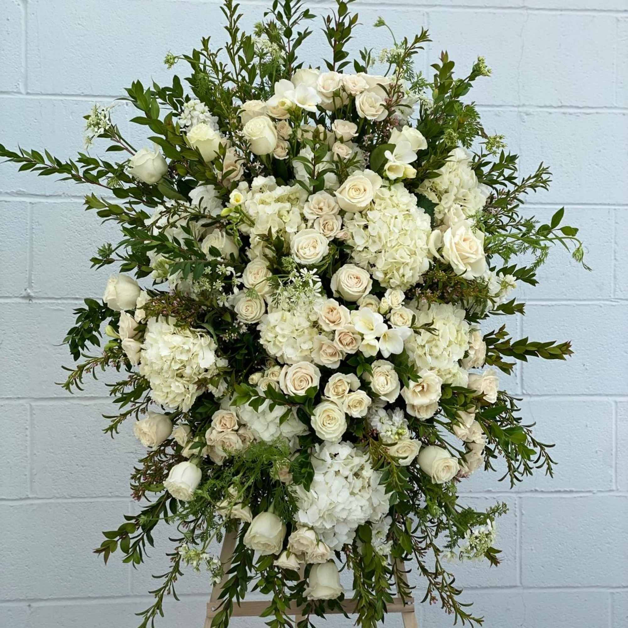 Large white floral standing arrangement on an easel