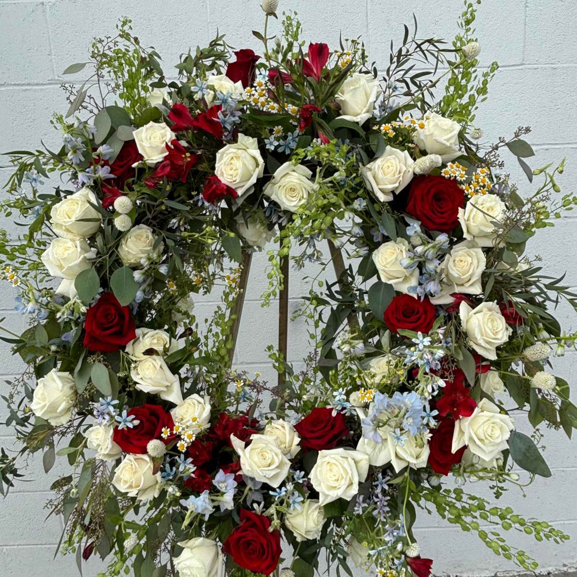 Large floral wreath with red and white roses and blue accents