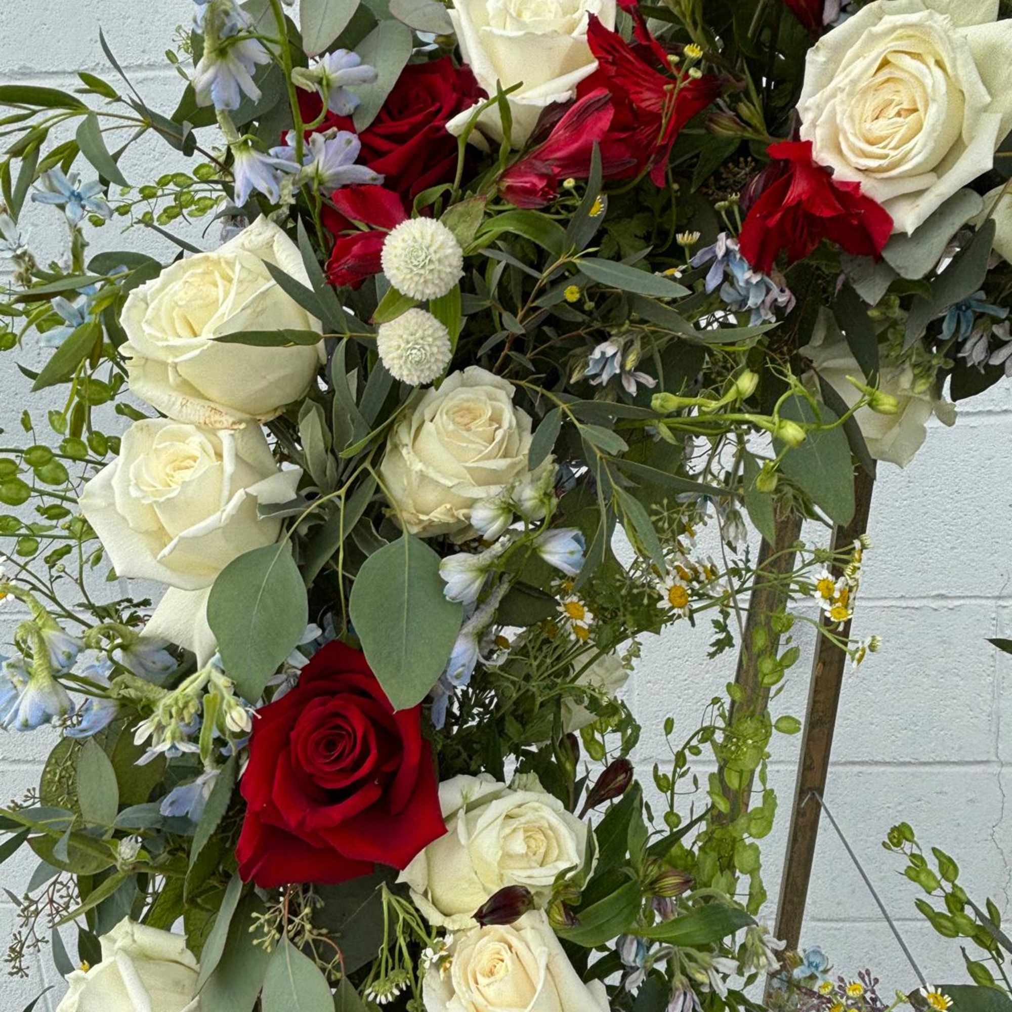 Tall arrangement of red and white roses with mixed filler flowers