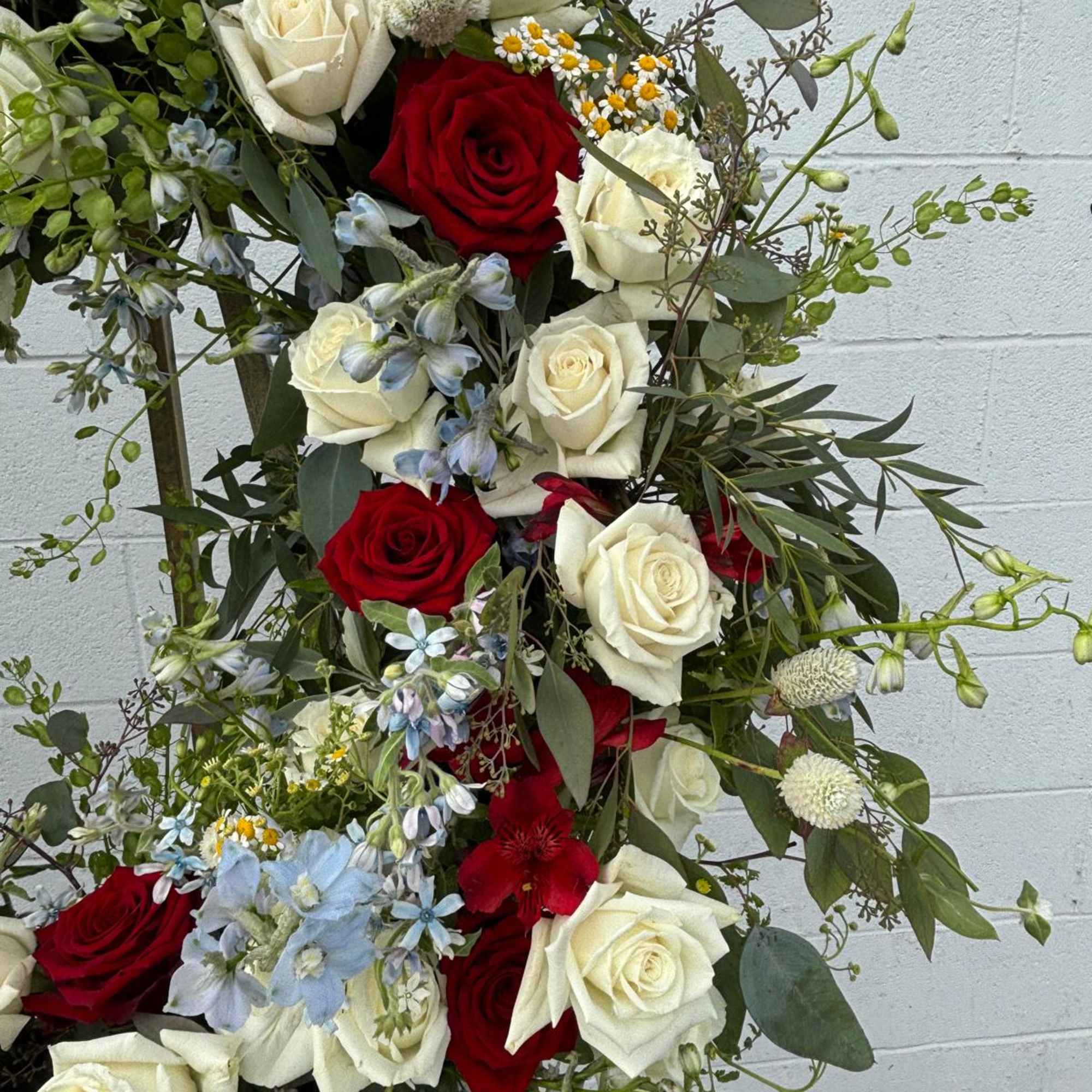 Tall bouquet of red and white roses with blue accent flowers