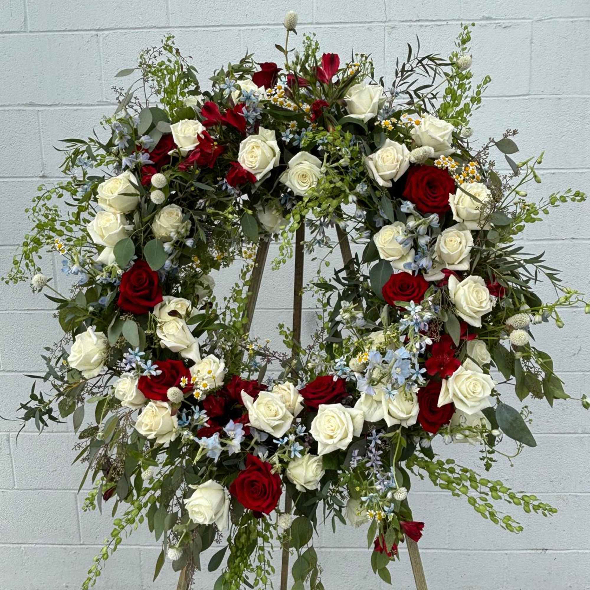 Large floral wreath of red and white roses on a stand