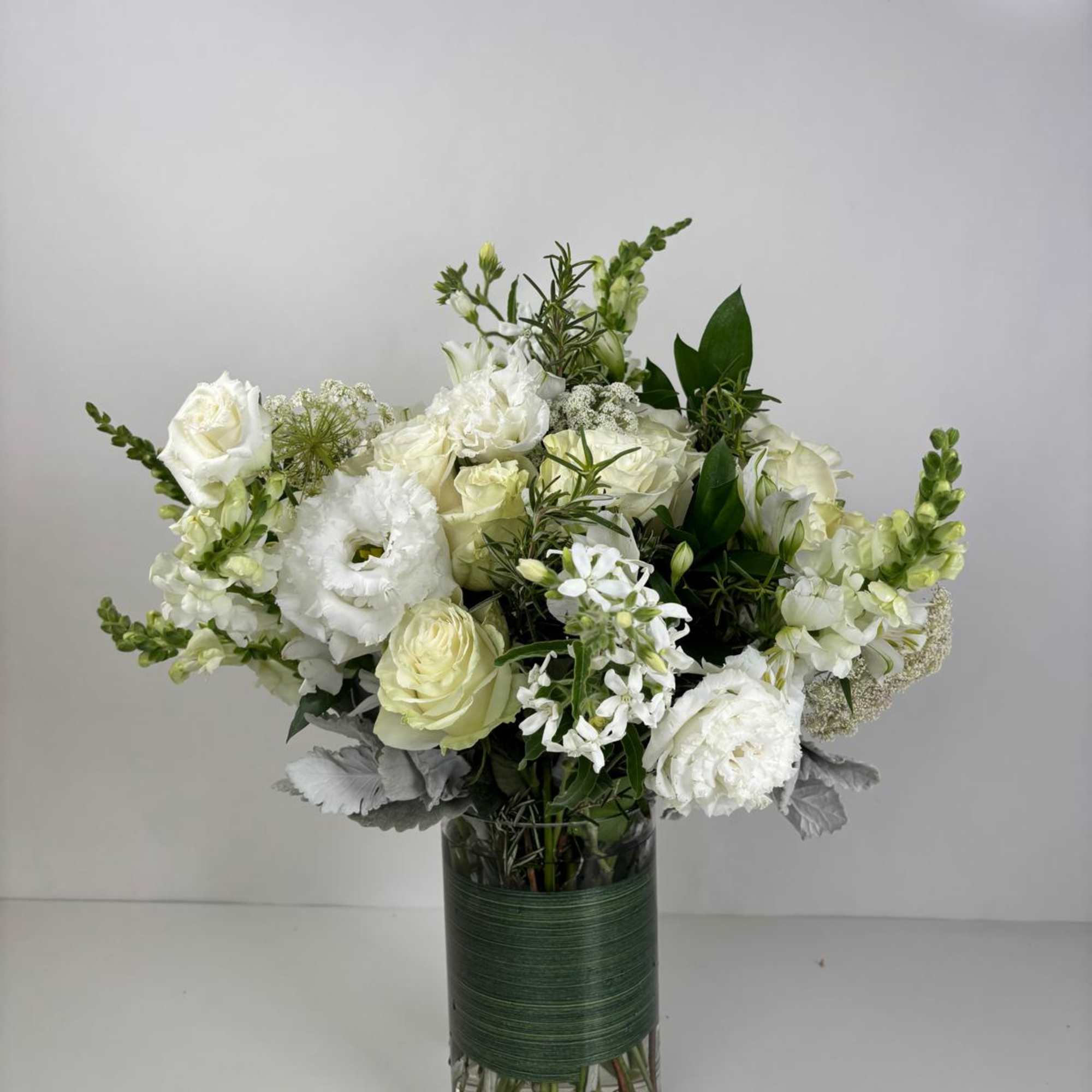 White roses and mixed white blooms arranged in a glass vase