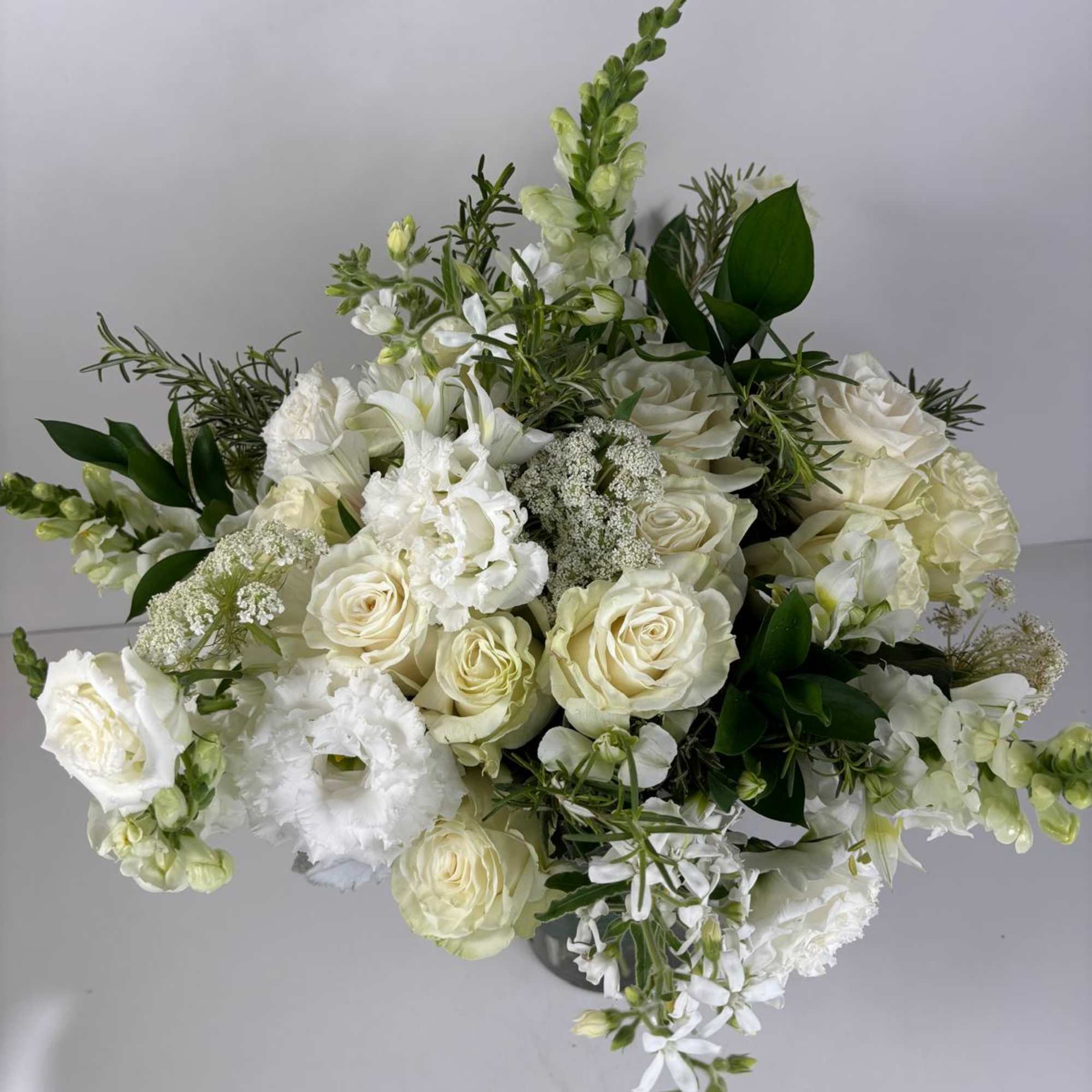 White rose and snapdragon bouquet with greenery in a vase