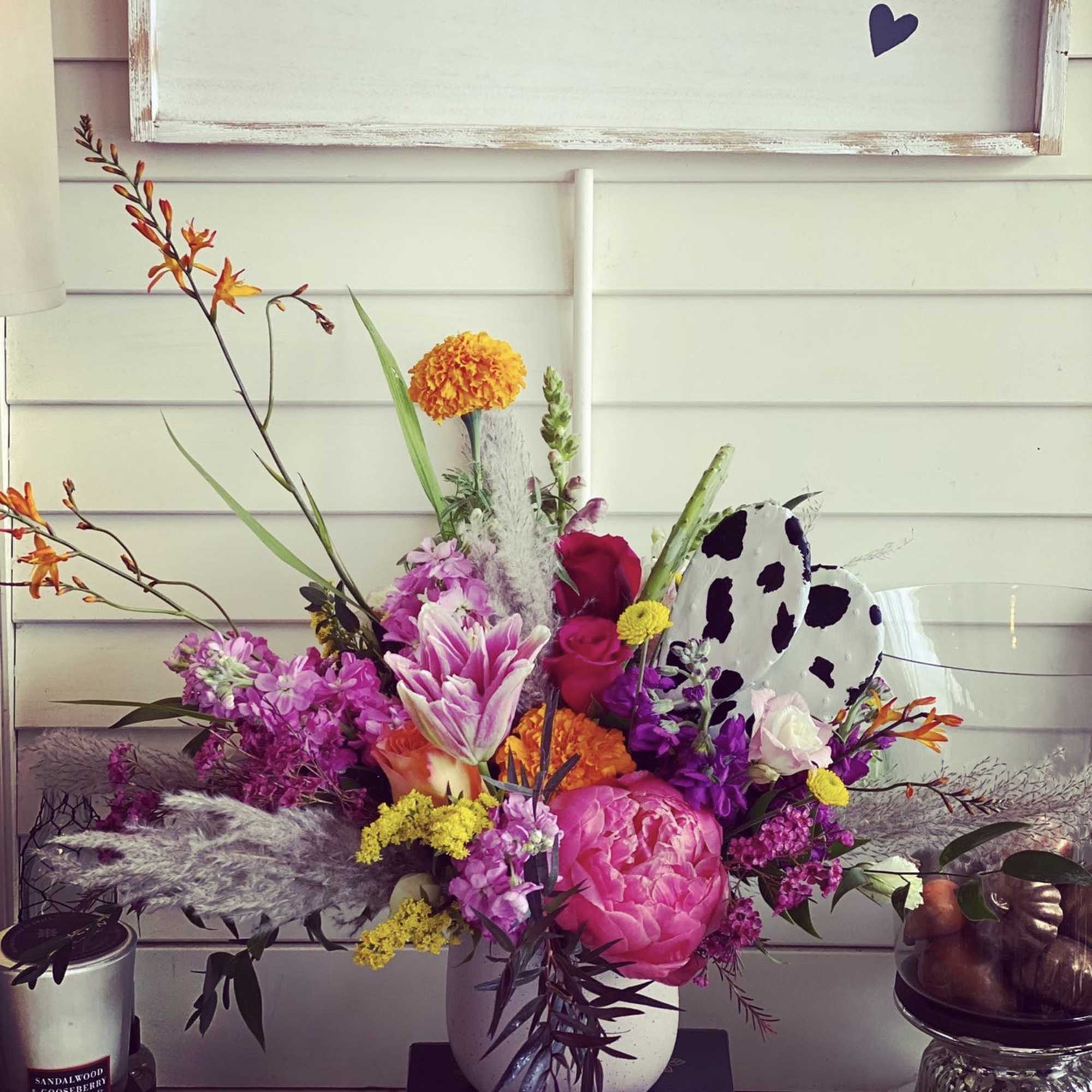 Bright mixed bouquet in a white vase with pink, orange, and purple flowers