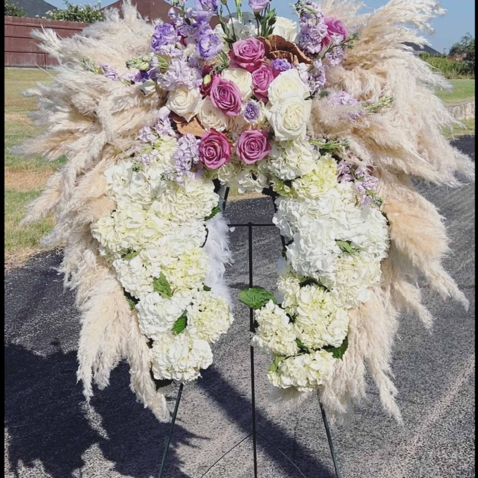 Large floral standing arrangement with pink roses, white blooms, and pampas grass