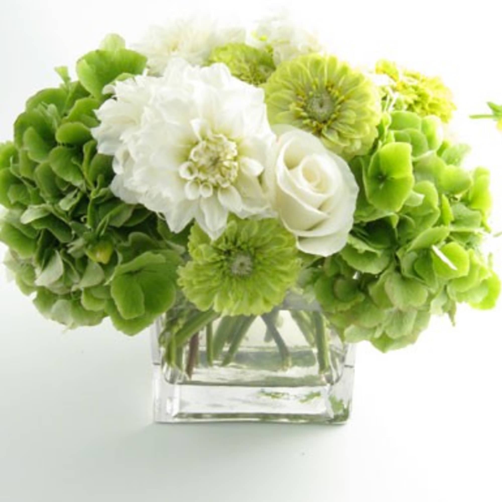 Green and white flower arrangement in a square glass vase