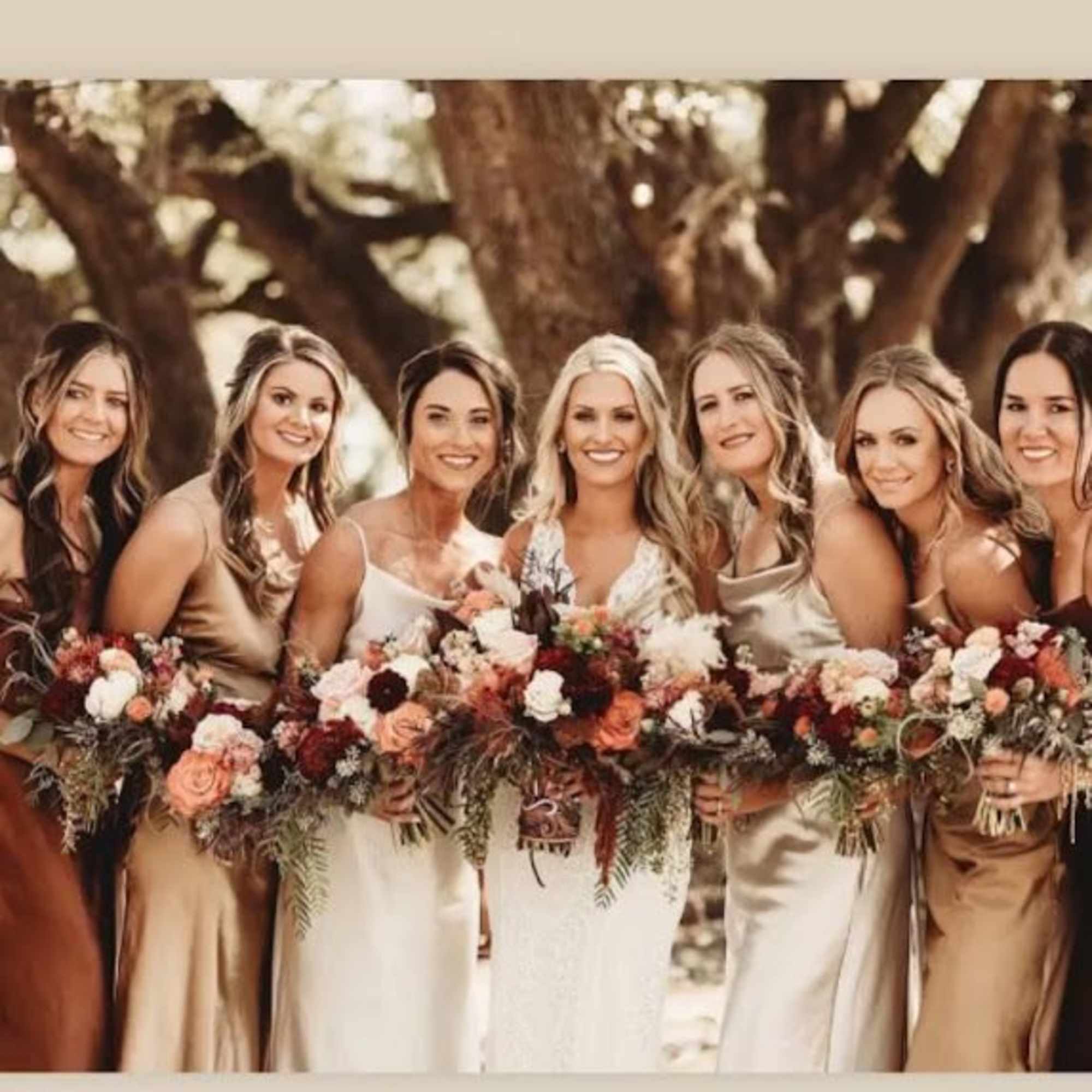 Bridesmaids holding mixed bouquets in warm neutral tones