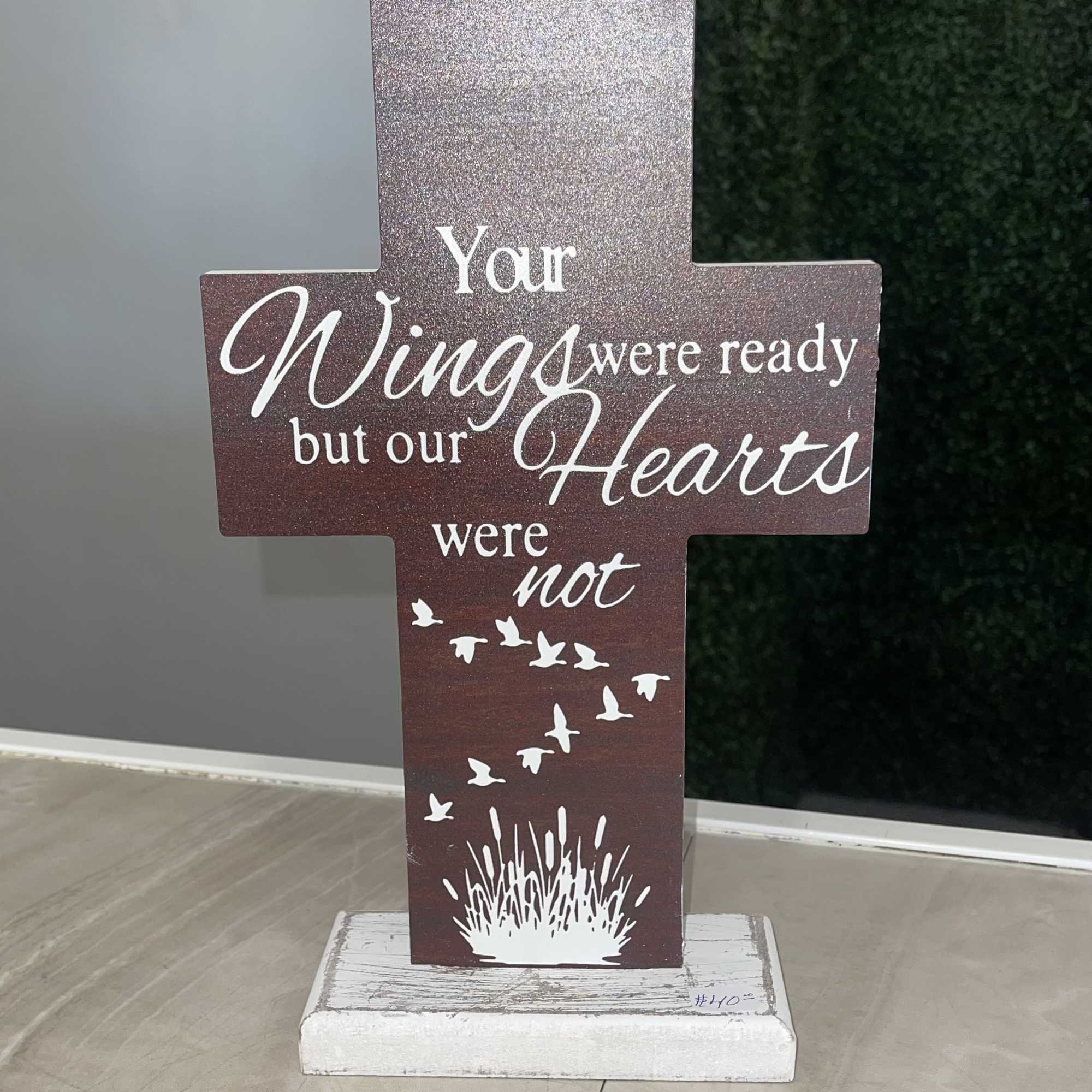 Cross-shaped memorial sign with the words "Your Wings were ready but our Hearts were not"