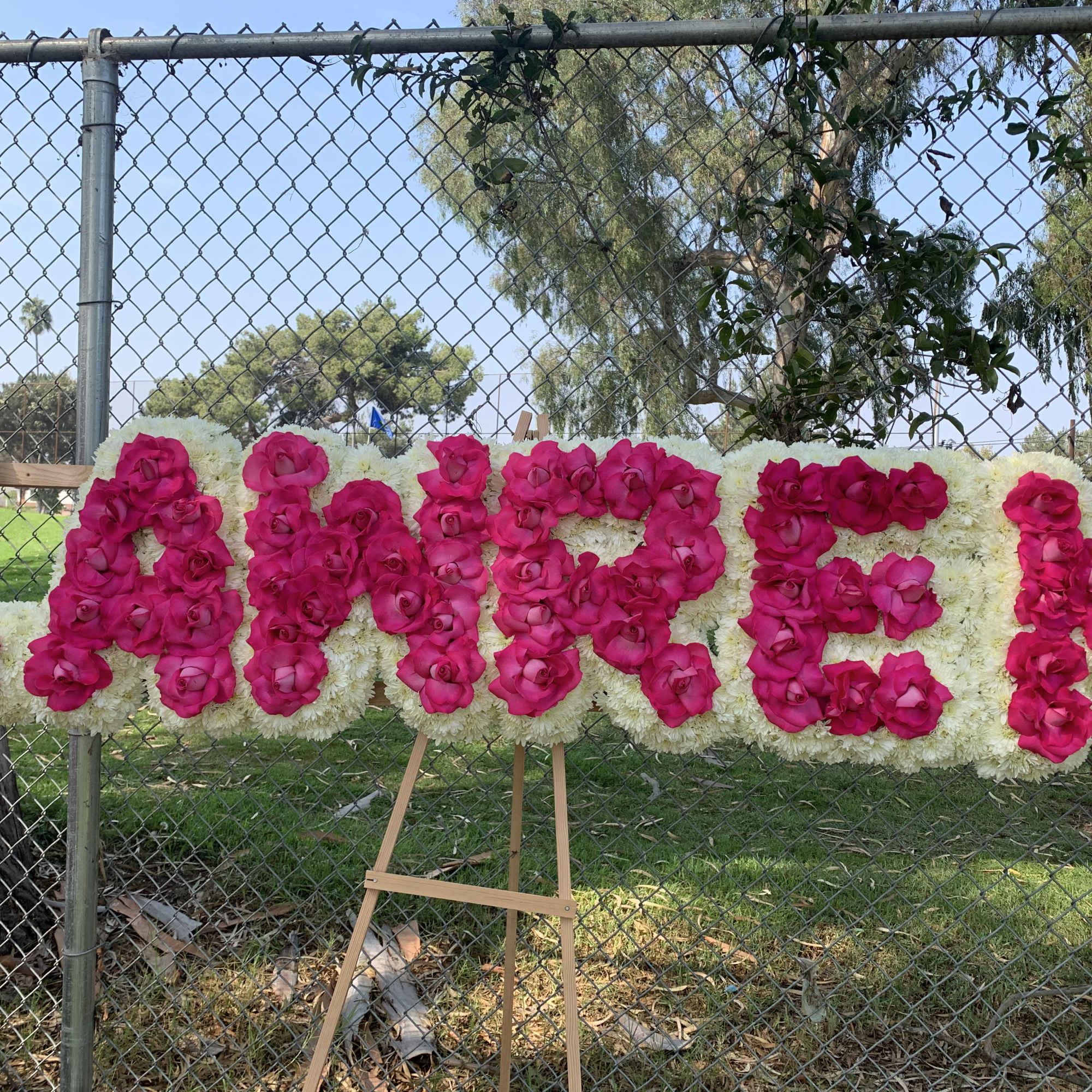 Large floral sign spelling "LAVEN" in pink roses on white flowers