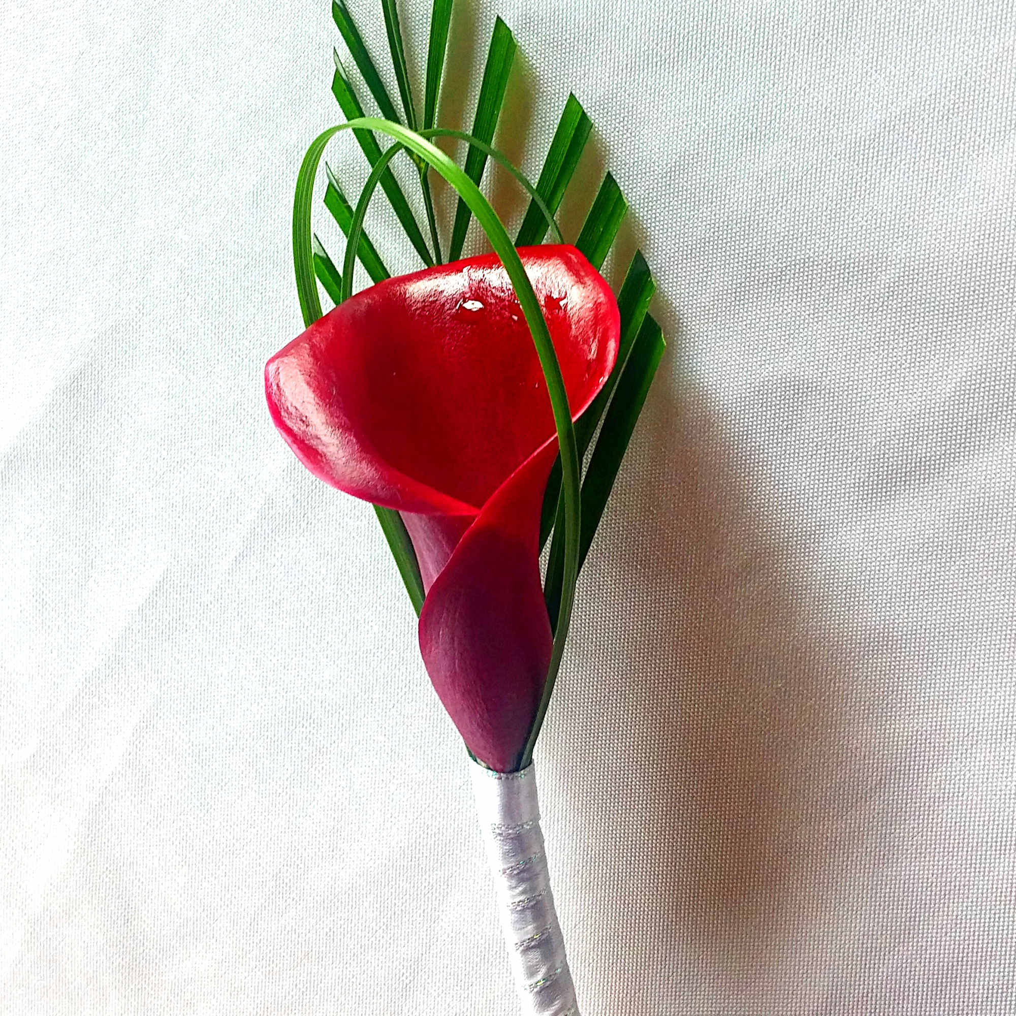 Red calla lily boutonniere with green palm fronds