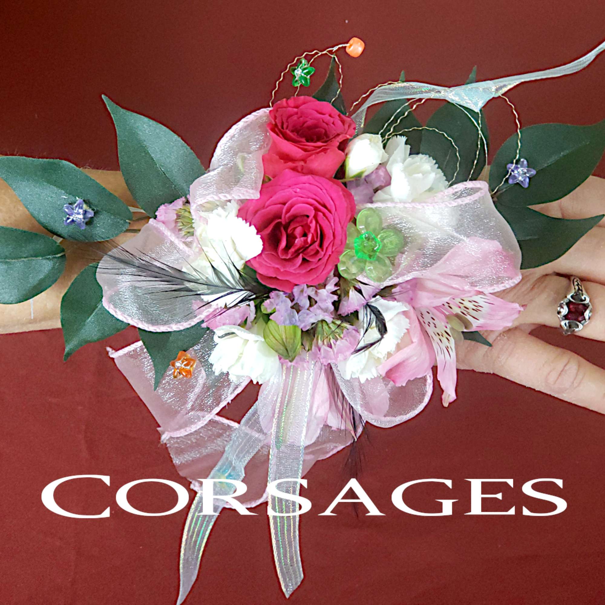 Pink and white floral corsage with ribbon and greenery
