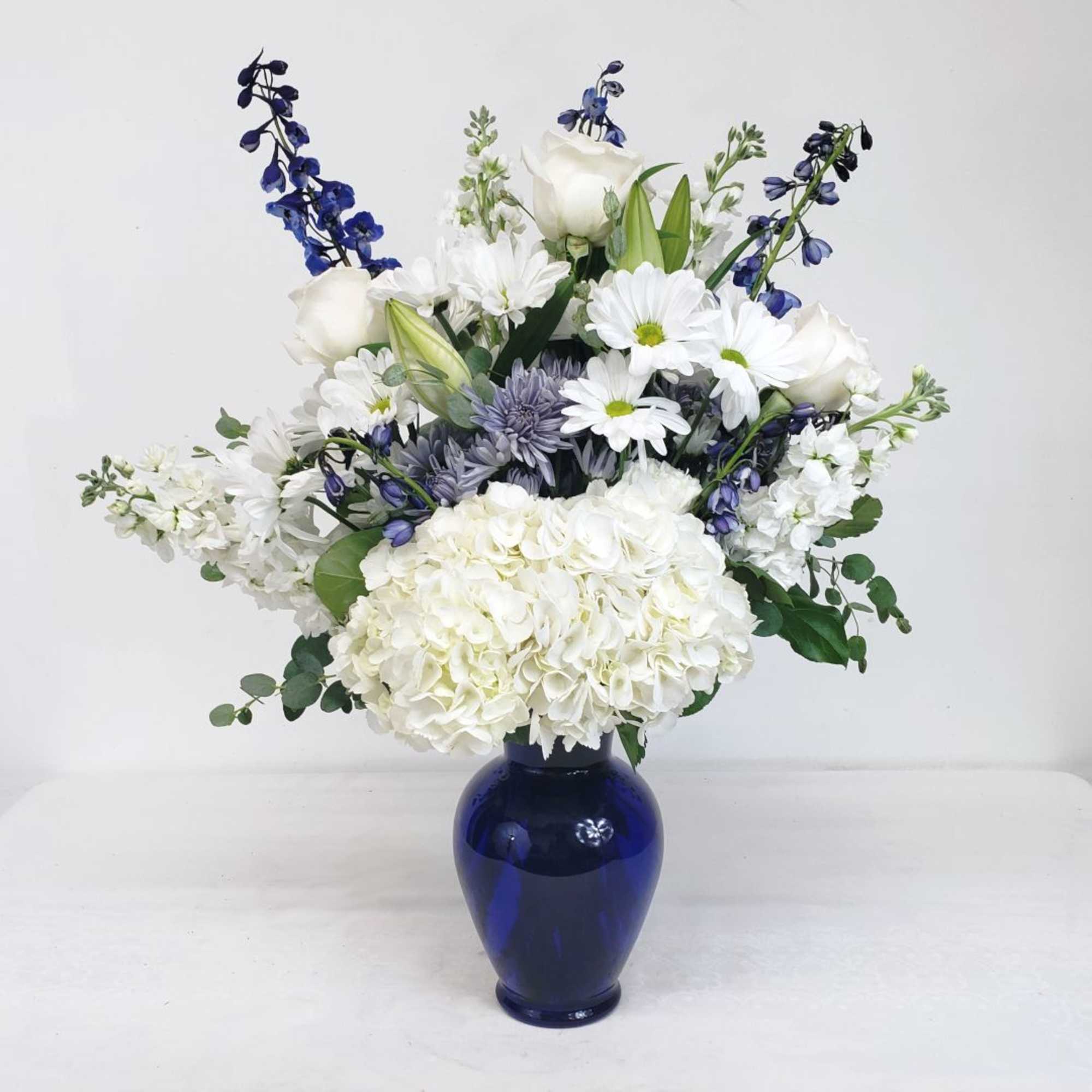 White and blue mixed flower arrangement in a cobalt vase