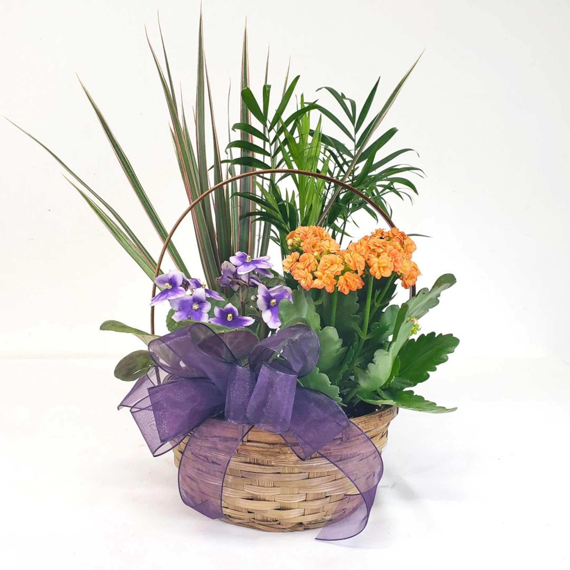 Basket arrangement with purple and orange flowers and a large purple ribbon